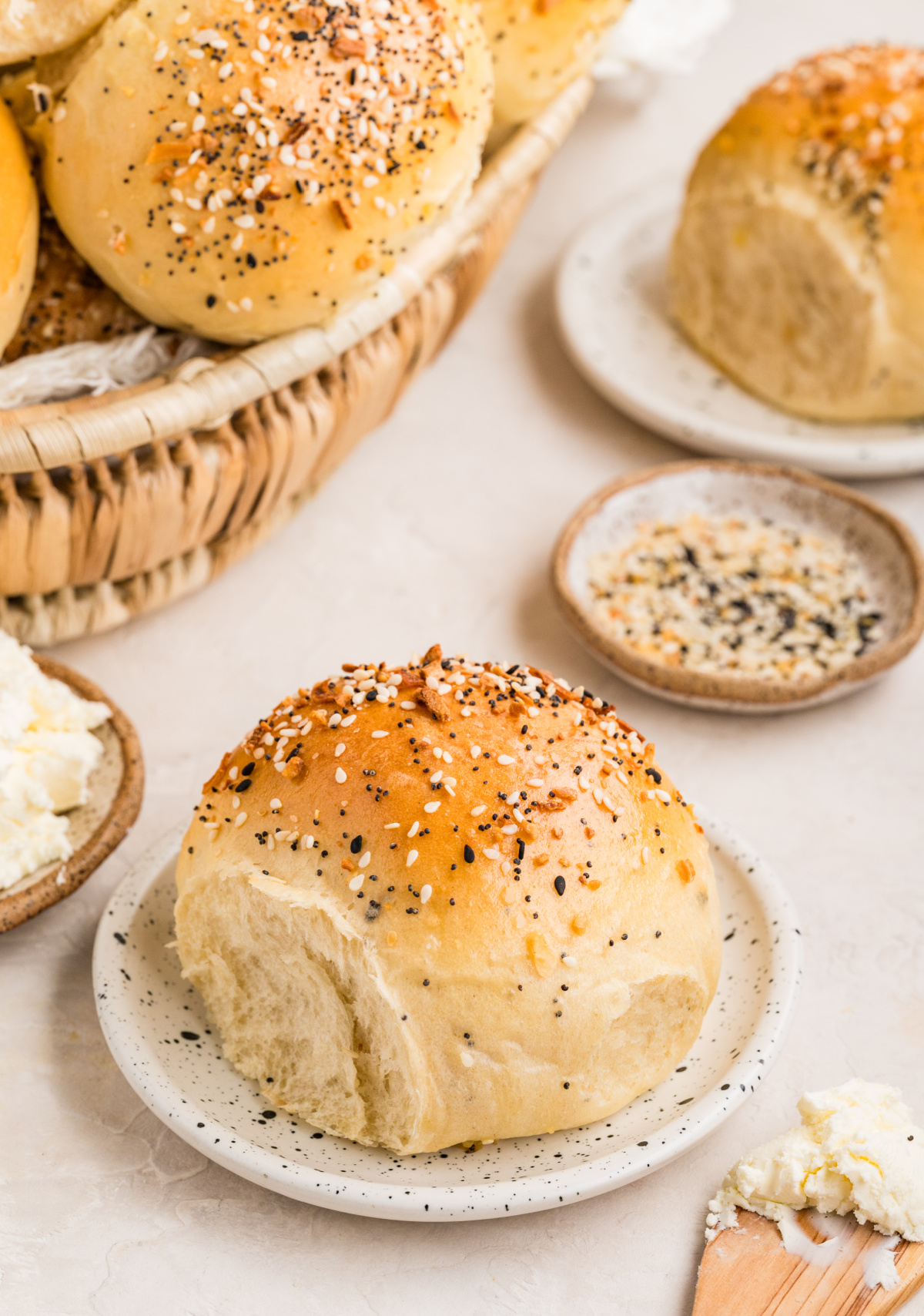 Everything bagel rolls baked until golden, topped with sesame seeds, poppy seeds, garlic, and onion, with one roll torn open to show the soft, chewy interior.