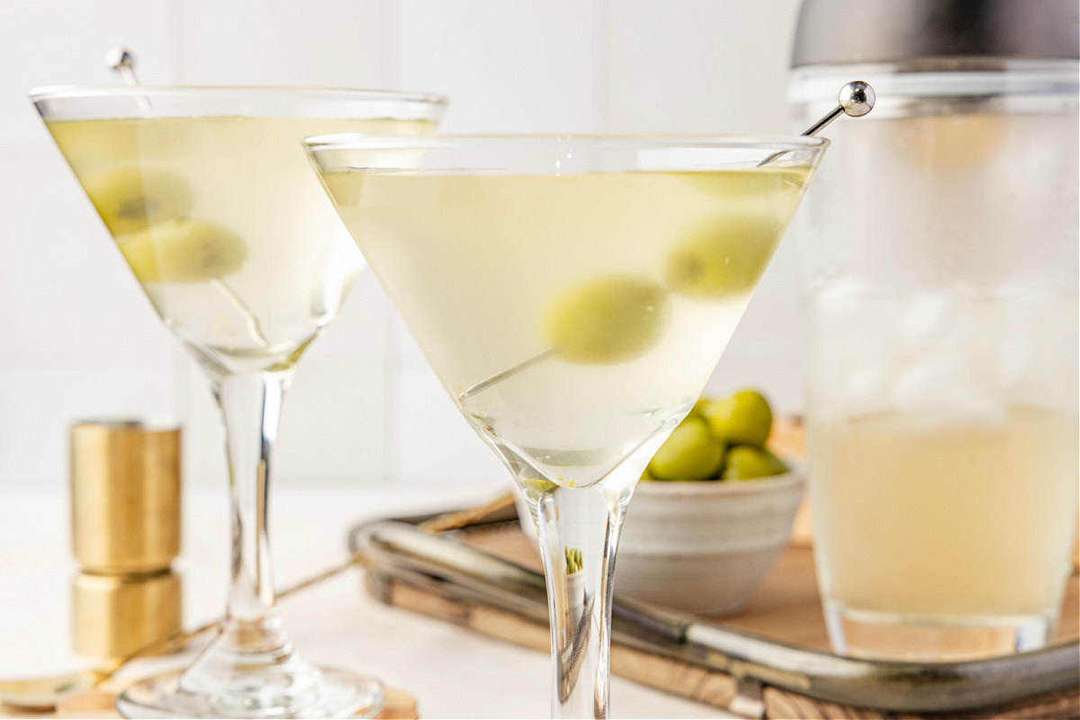 A very dirty martini resting in a chilled glass with green olives suspended in the pale, briny cocktail.