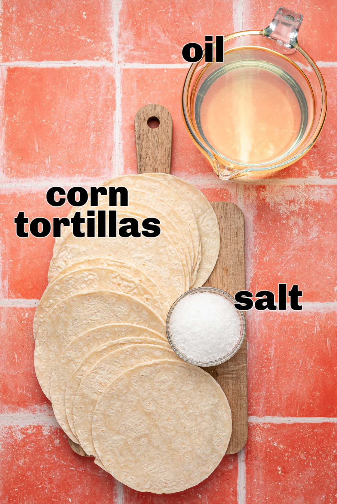 Corn tortillas, oil, and salt arranged on a cutting board as the base ingredients for easy fried tortilla chips.