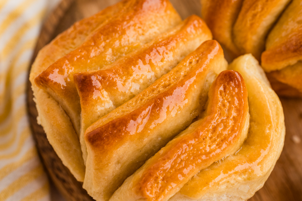 Close view of a golden pull-apart roll with glossy honey butter coating the folded layers.