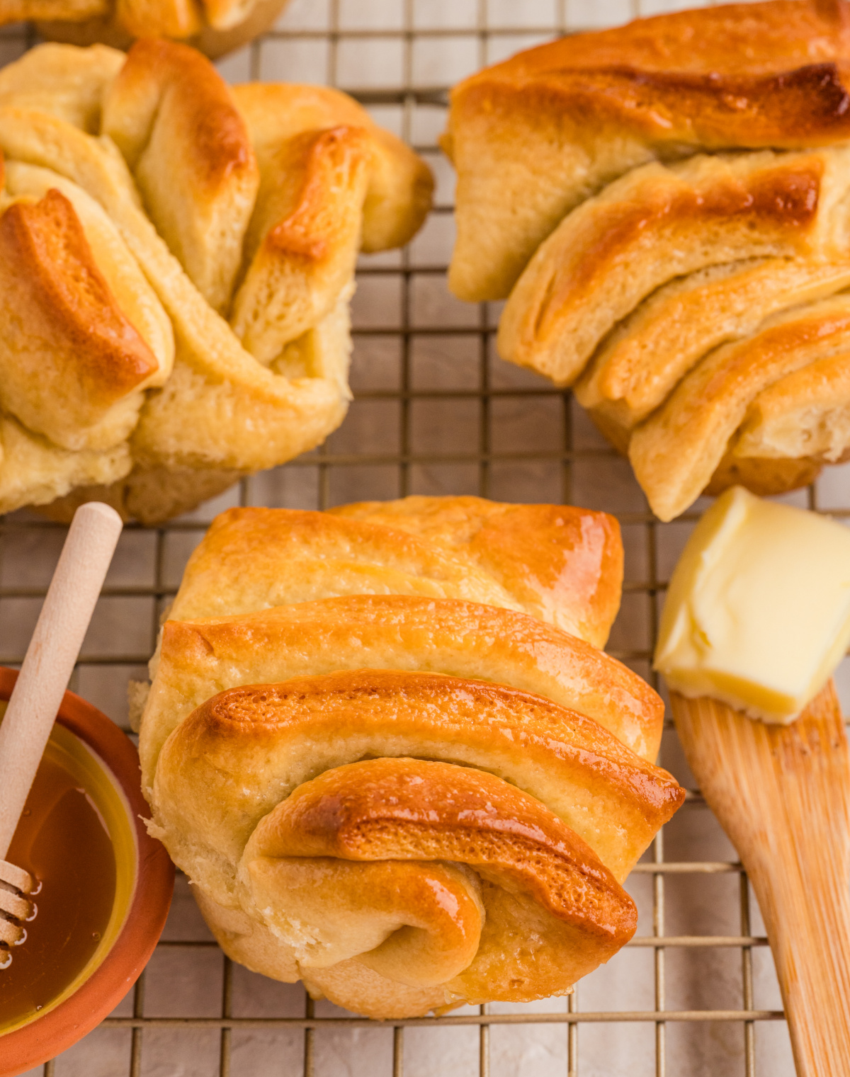Honey butter pull-apart rolls cooling on a wire rack with glossy tops and soft folded layers.