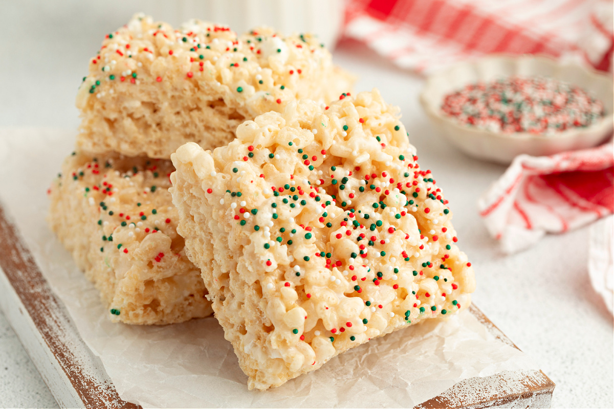 Stacked sugar cookie&ndash;flavored Rice Krispie treat squares covered in red, green, and white holiday sprinkles.