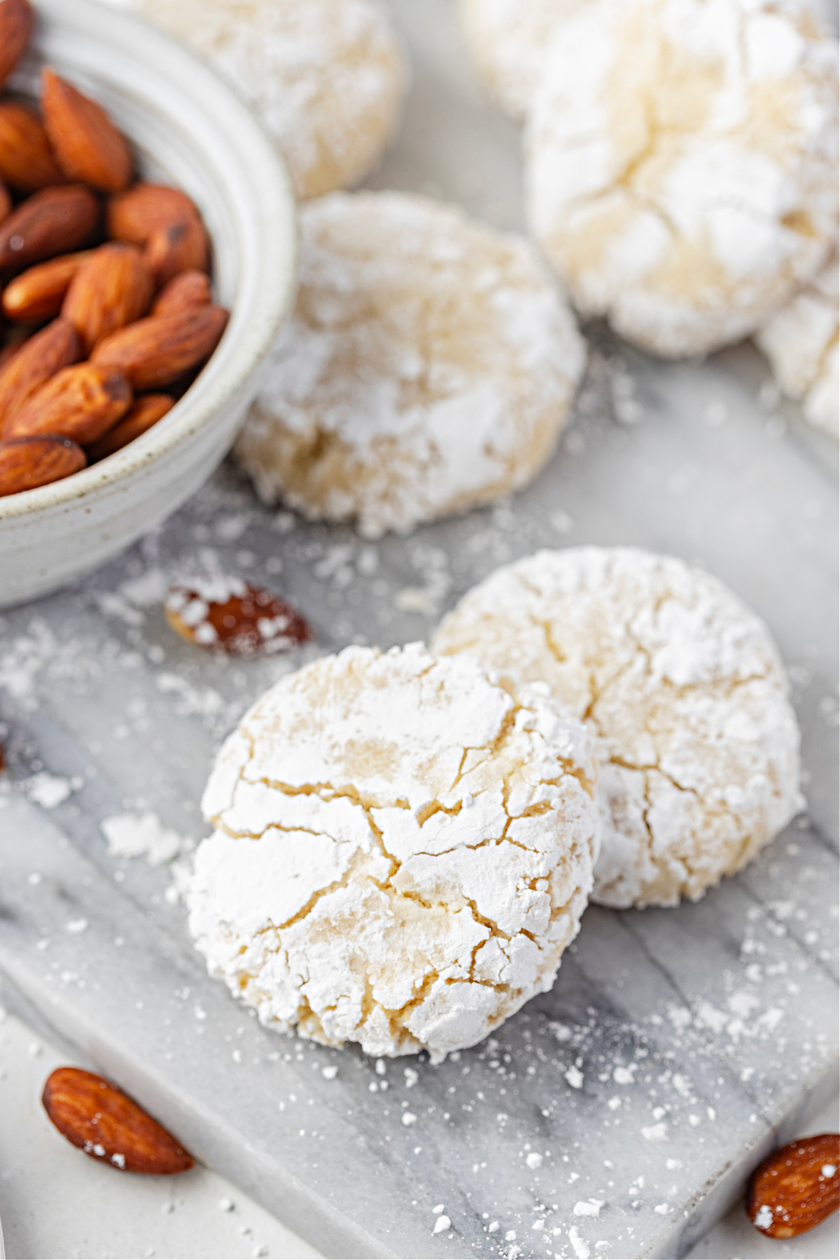 A close-up stack of snowy, crackled almond cookies showing their soft, tender centers.
