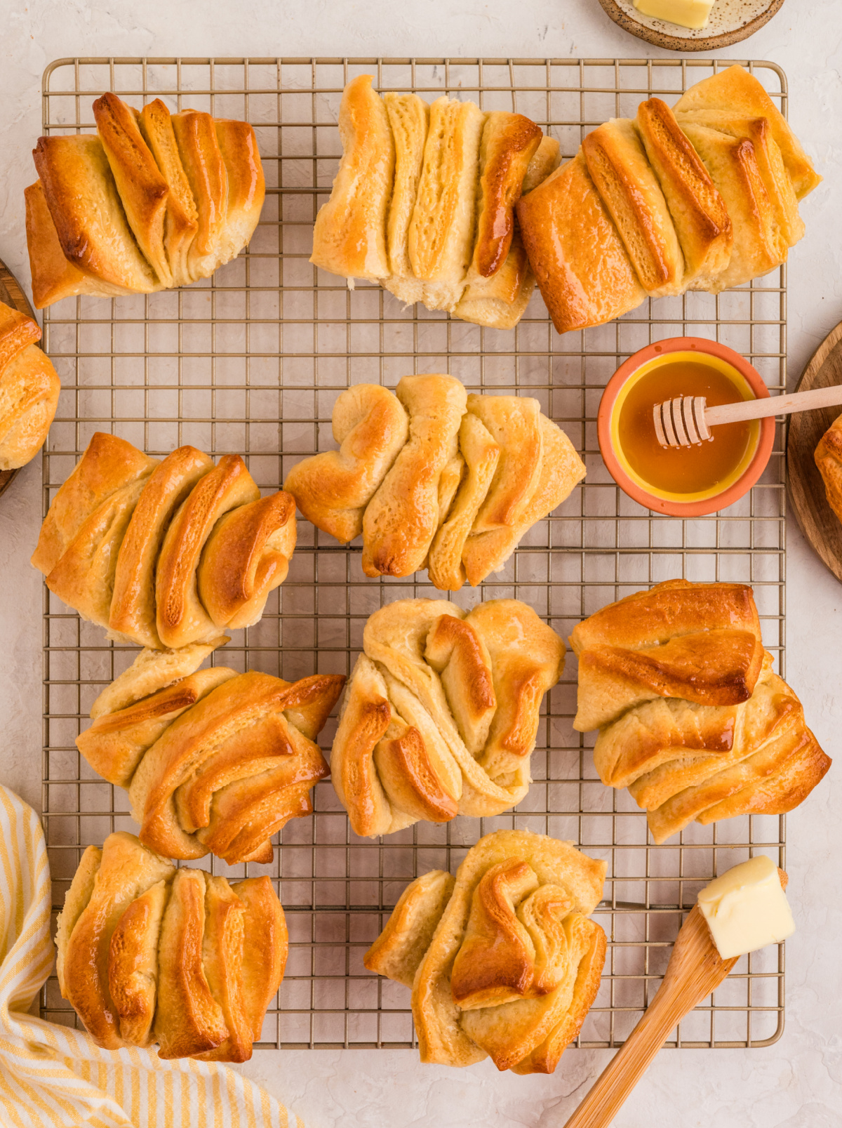 Soft honey butter pull-apart rolls cooling on a wire rack with a golden layered finish.