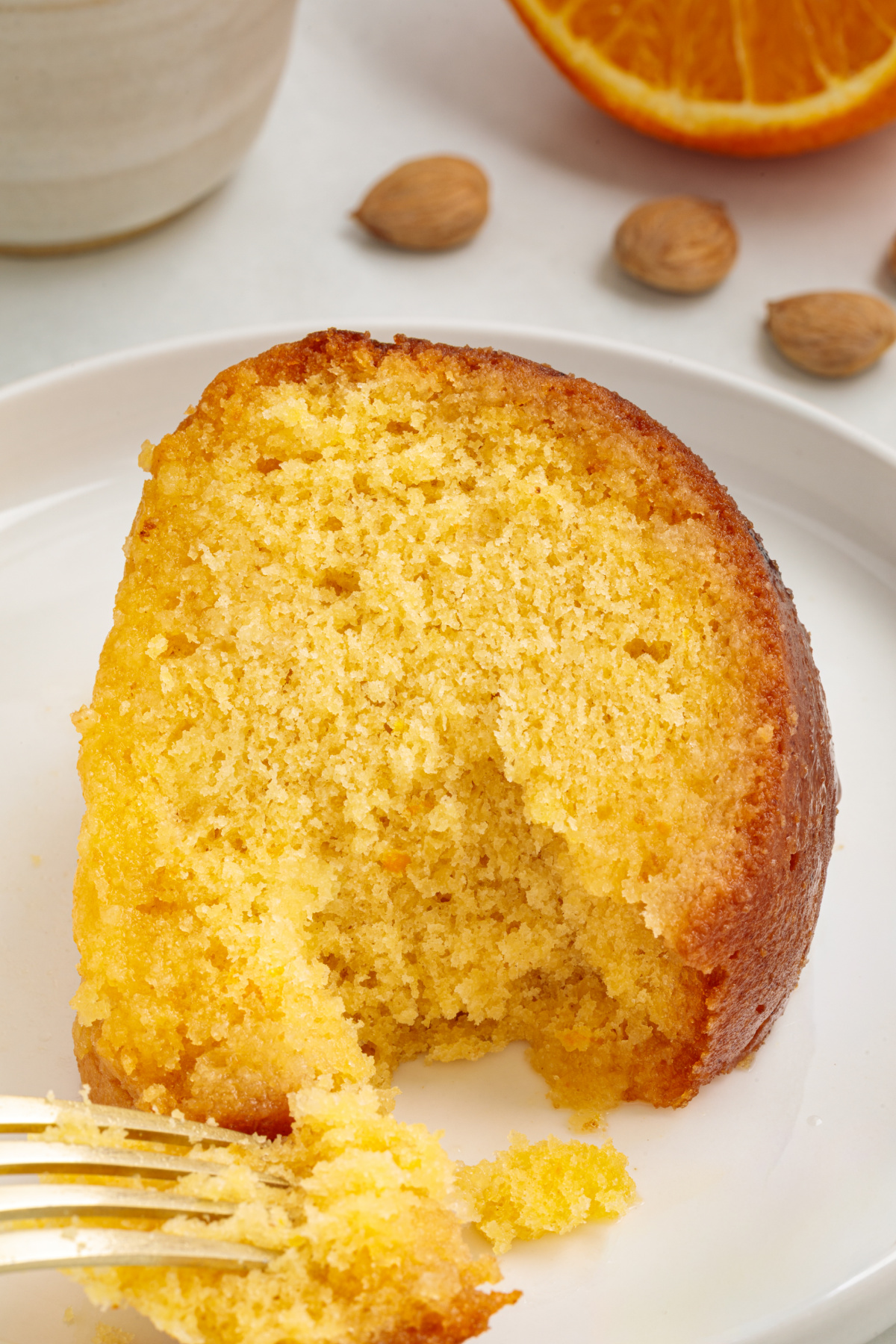 Moist citrus almond cake crumb with a fork breaking into the syrup-soaked center.