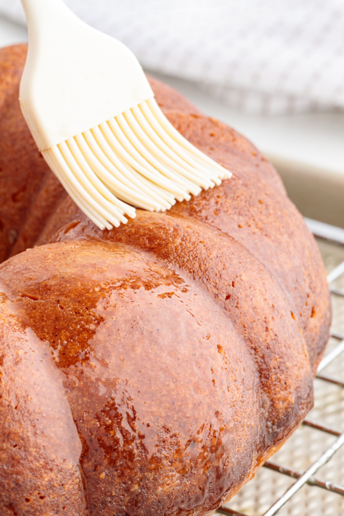 Italian Hangover Cake being brushed with warm citrus Amaretto syrup while cooling on a rack.