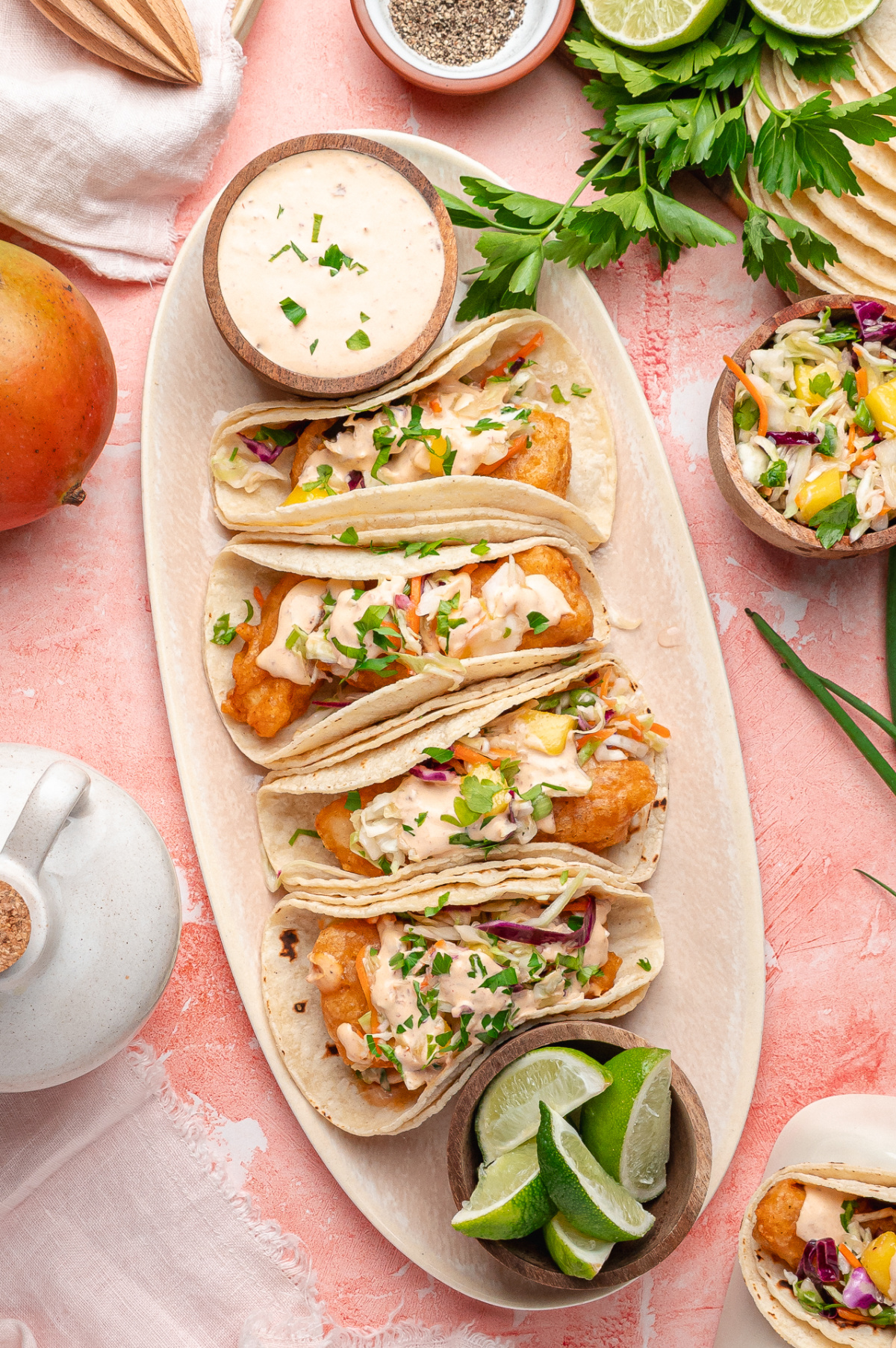 Beer-battered fish tacos filled with crispy cod, mango slaw, and chipotle lime sauce served with lime wedges.