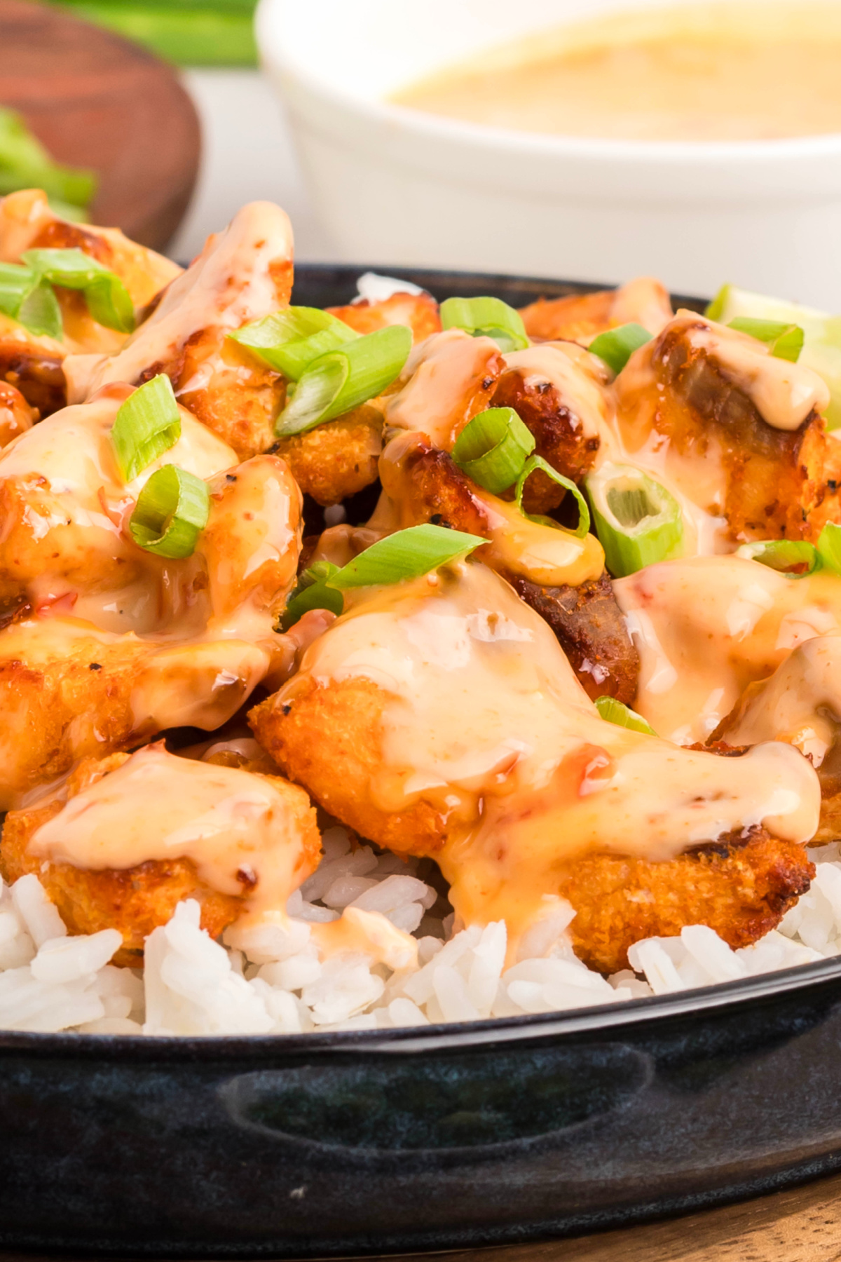 Air fryer bang bang salmon bites with crisp edges, creamy sauce, and sliced green onions served over white rice.