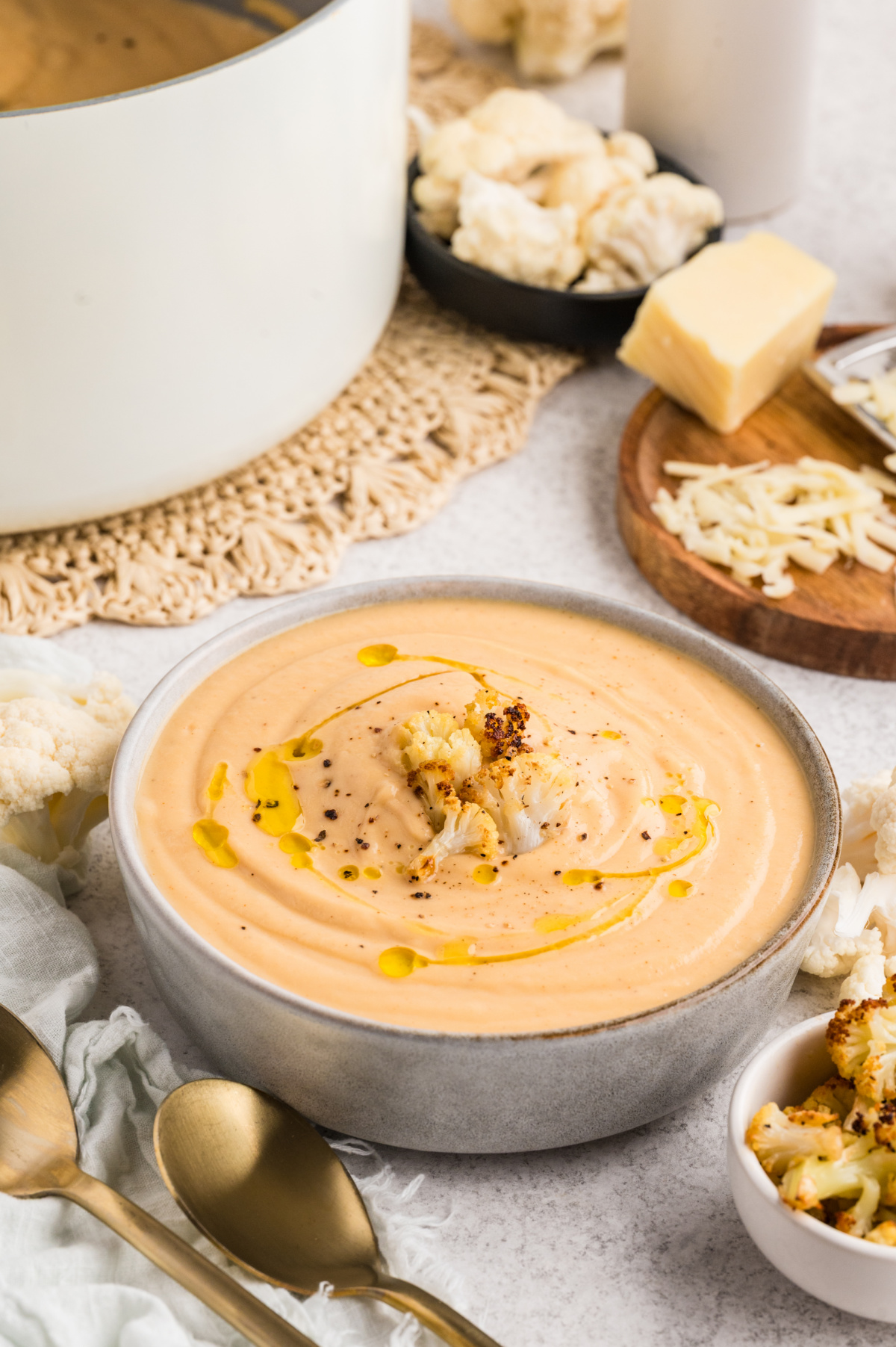 Roasted Cauliflower Soup finished with olive oil, black pepper, and caramelized cauliflower florets in a shallow bowl.