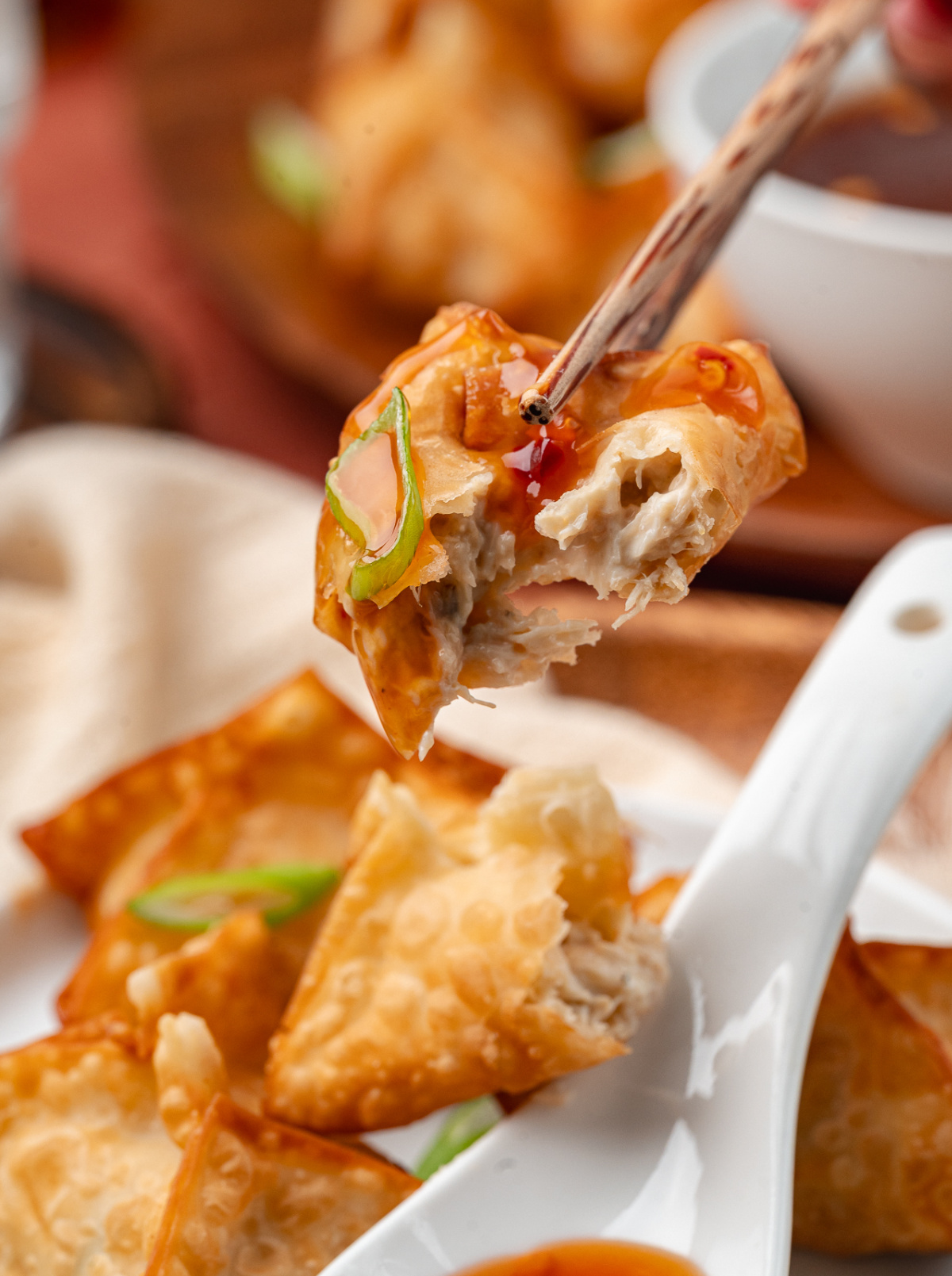 Crab rangoon with a crisp golden wrapper and creamy crab filling, served with a sweet and spicy dipping sauce on a white plate.