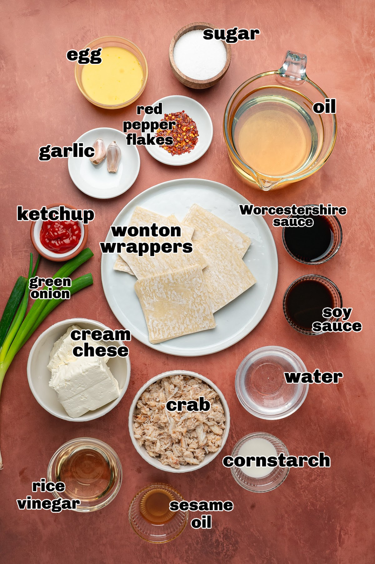 Ingredients for making crab rangoon and sweet and spicy dipping sauce, including cream cheese, crab, wonton wrappers, green onions, garlic, and sauce components.
