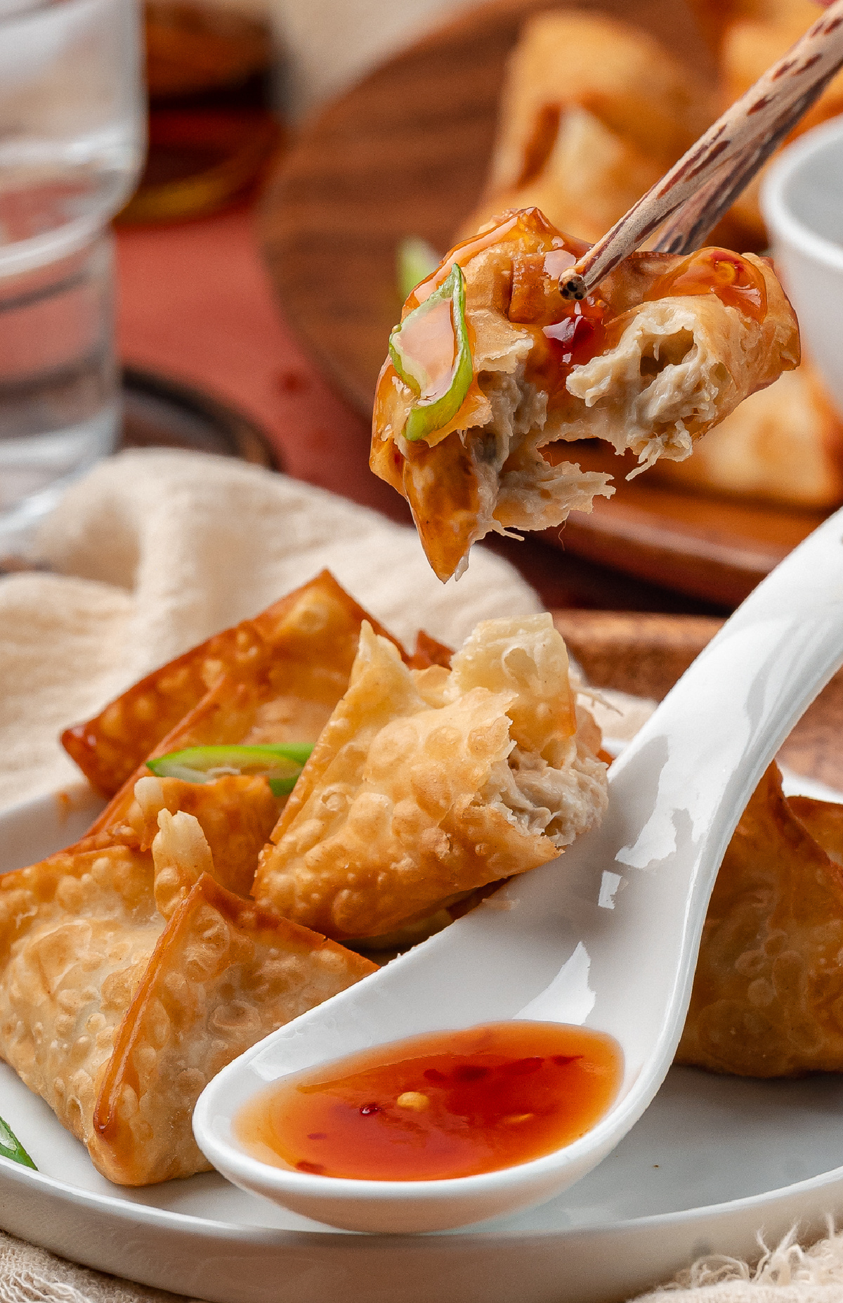 Crab rangoon bite showing creamy crab filling inside a crisp fried wonton wrapper with sweet and spicy dipping sauce.