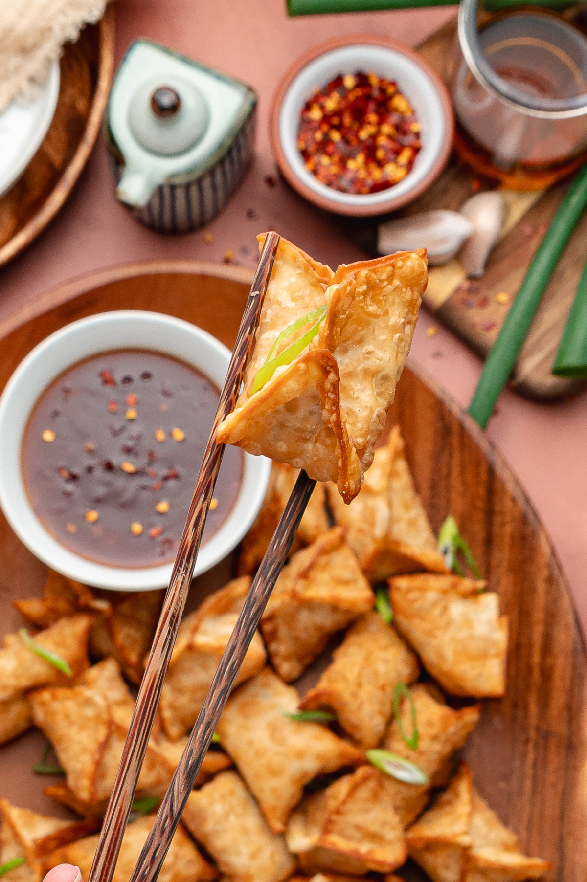 Crisp cream cheese and crab wonton held with chopsticks and dipped into sweet and spicy sauce.