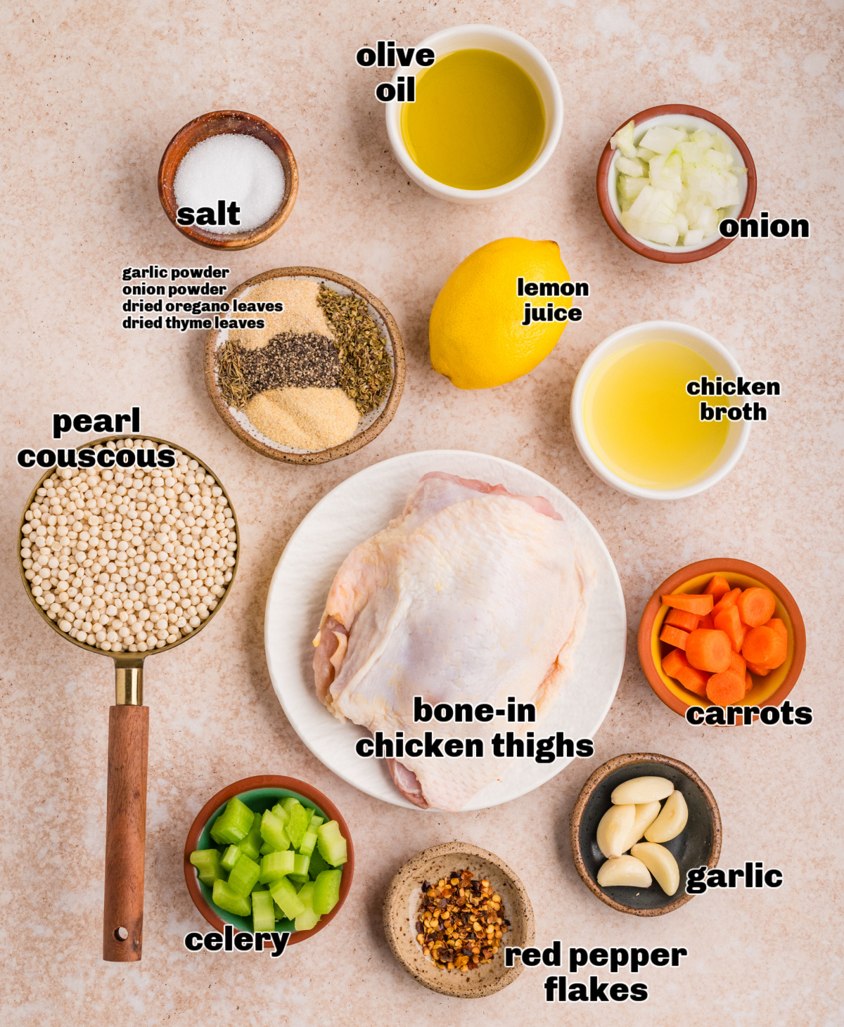 Ingredients for chicken thighs and pearl couscous, including olive oil, lemon juice, broth, vegetables, herbs, and spices arranged on a countertop.