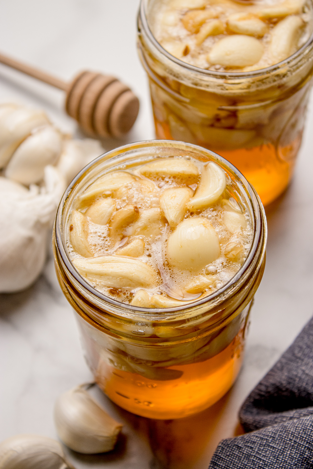 Fermented honey garlic actively bubbling in a mason jar, with whole garlic cloves floating as fermentation continues.