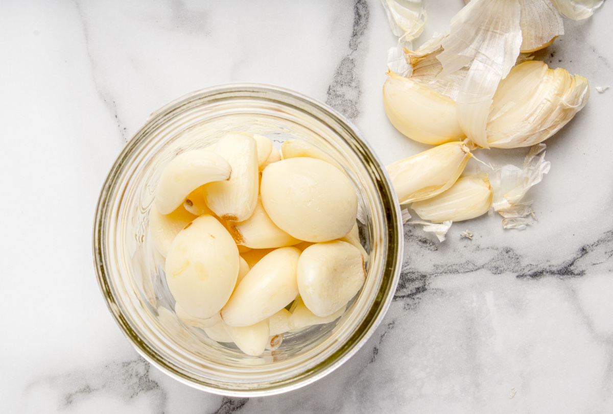 Peeled fresh garlic cloves placed in a wide-mouth mason jar before adding honey for fermentation.
