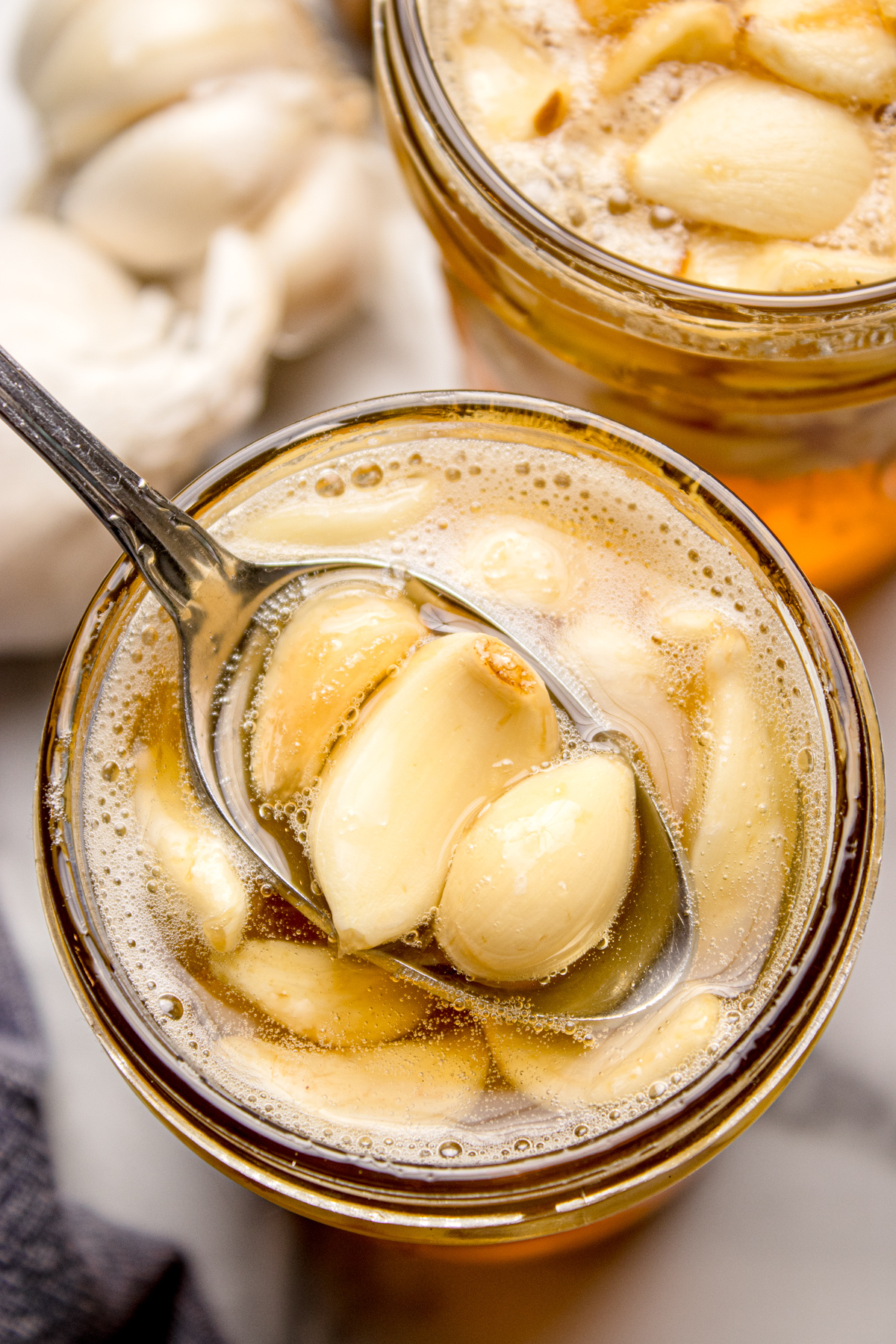 Fermented honey garlic with whole garlic cloves submerged in raw honey, showing bubbles from active fermentation.