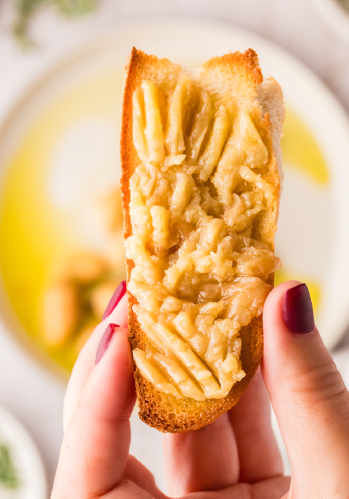 Garlic confit mashed and spread thickly onto toasted bread, shown close up.