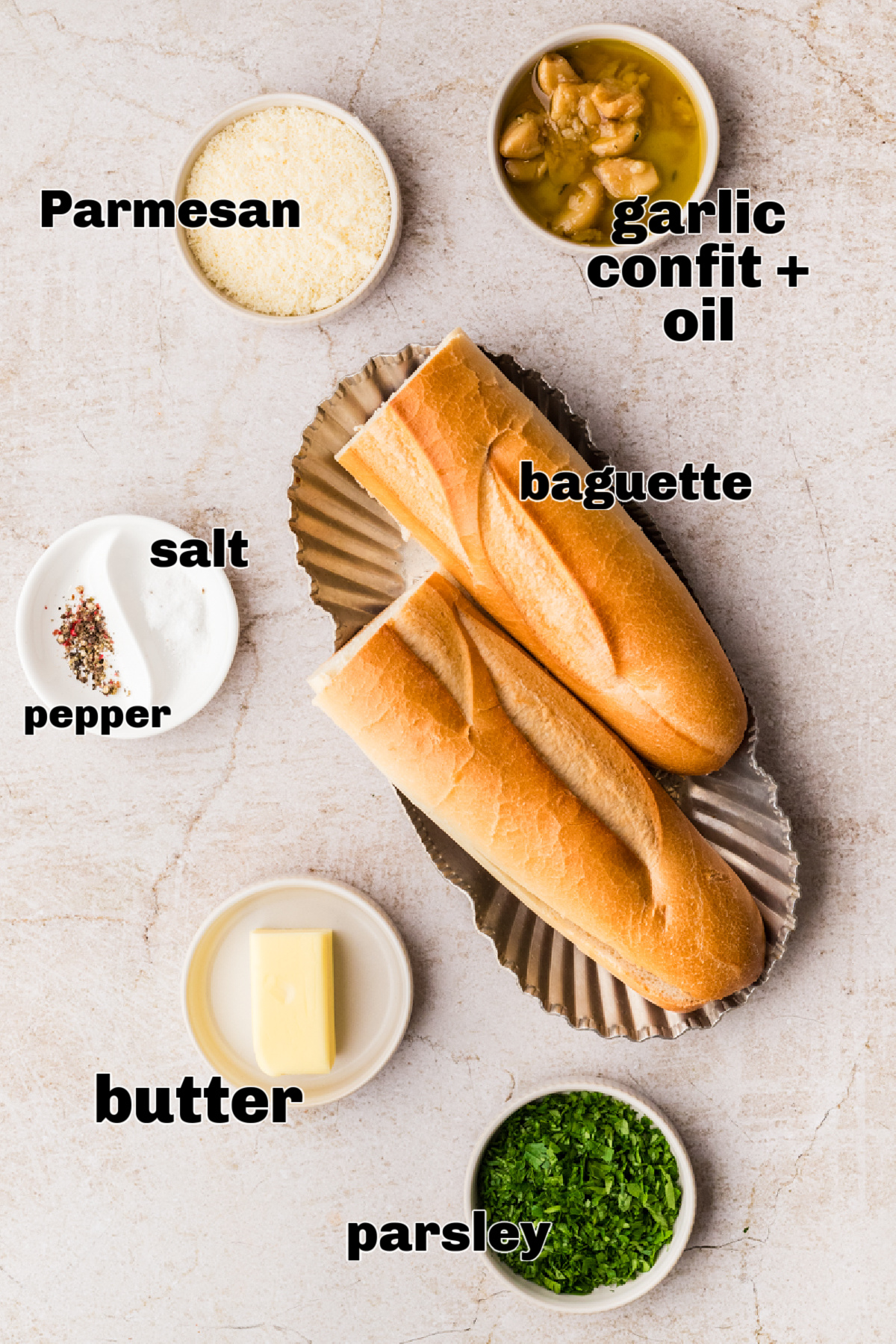 Ingredients for air fryer garlic bread including baguette, garlic confit with oil, butter, Parmesan, parsley, salt, and pepper