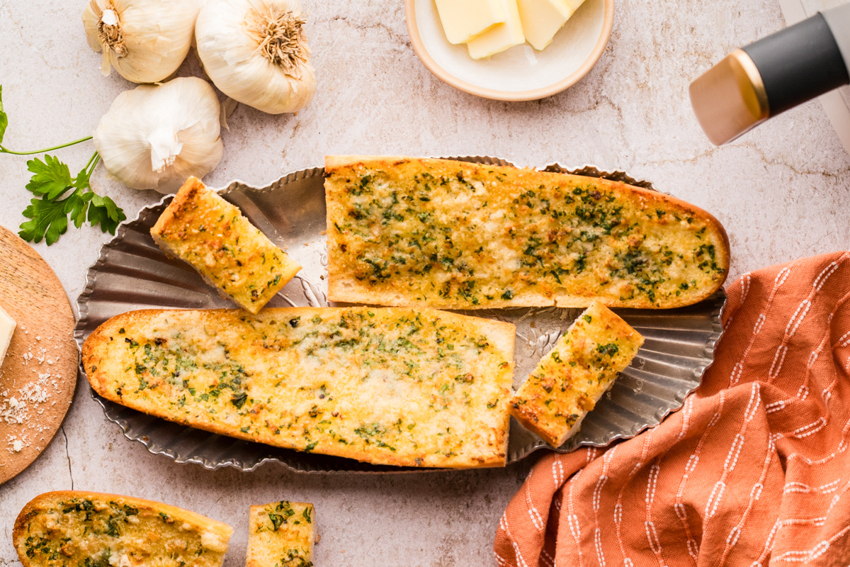 Garlic confit air fryer bread arranged on a platter with golden tops, parsley, and Parmesan