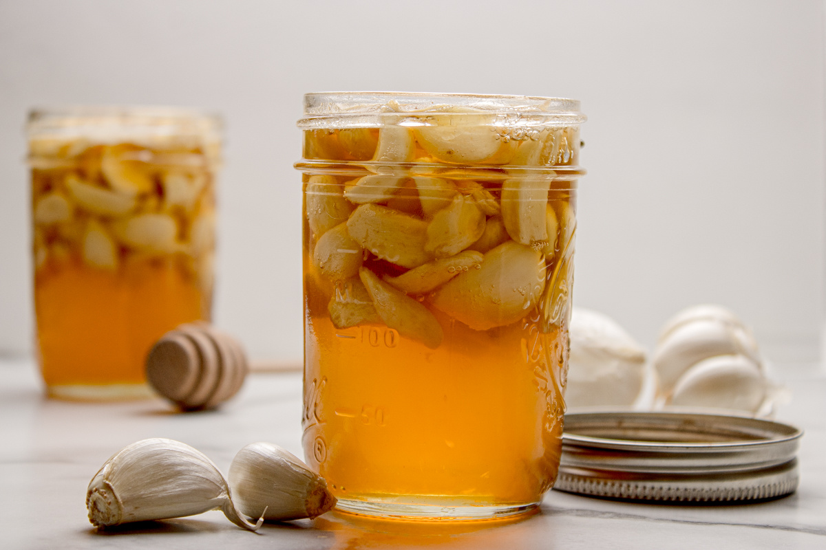 Fermented honey garlic in a mason jar with whole garlic cloves suspended in honey as fermentation develops.