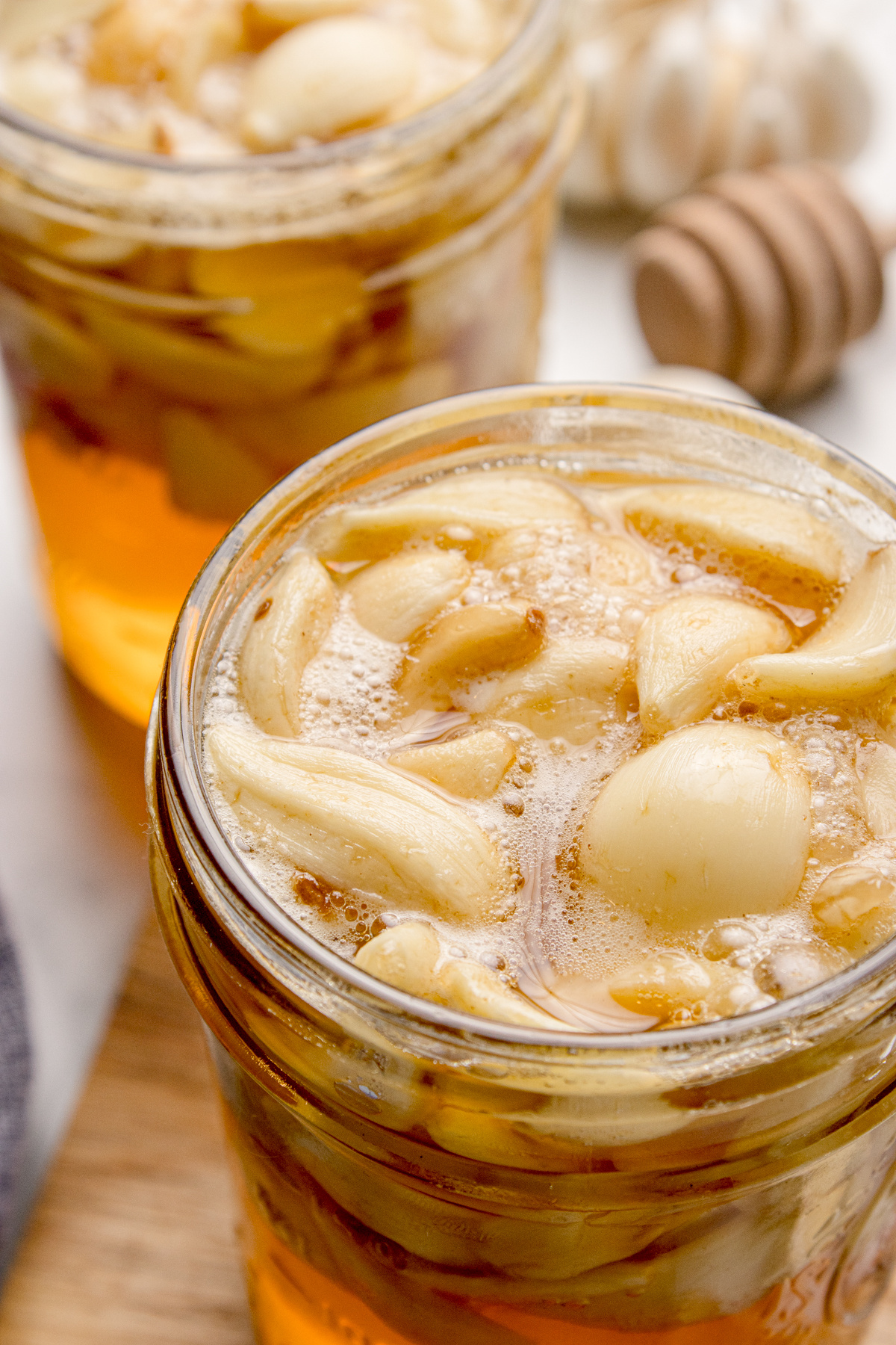 Fermented honey garlic with whole garlic cloves bubbling in loosened honey near the surface of the jar.