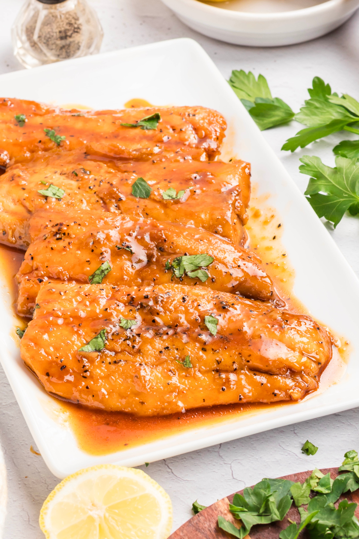 Honey glazed salmon fillets arranged on a platter, fully coated in a smooth honey glaze and finished with black pepper and parsley.