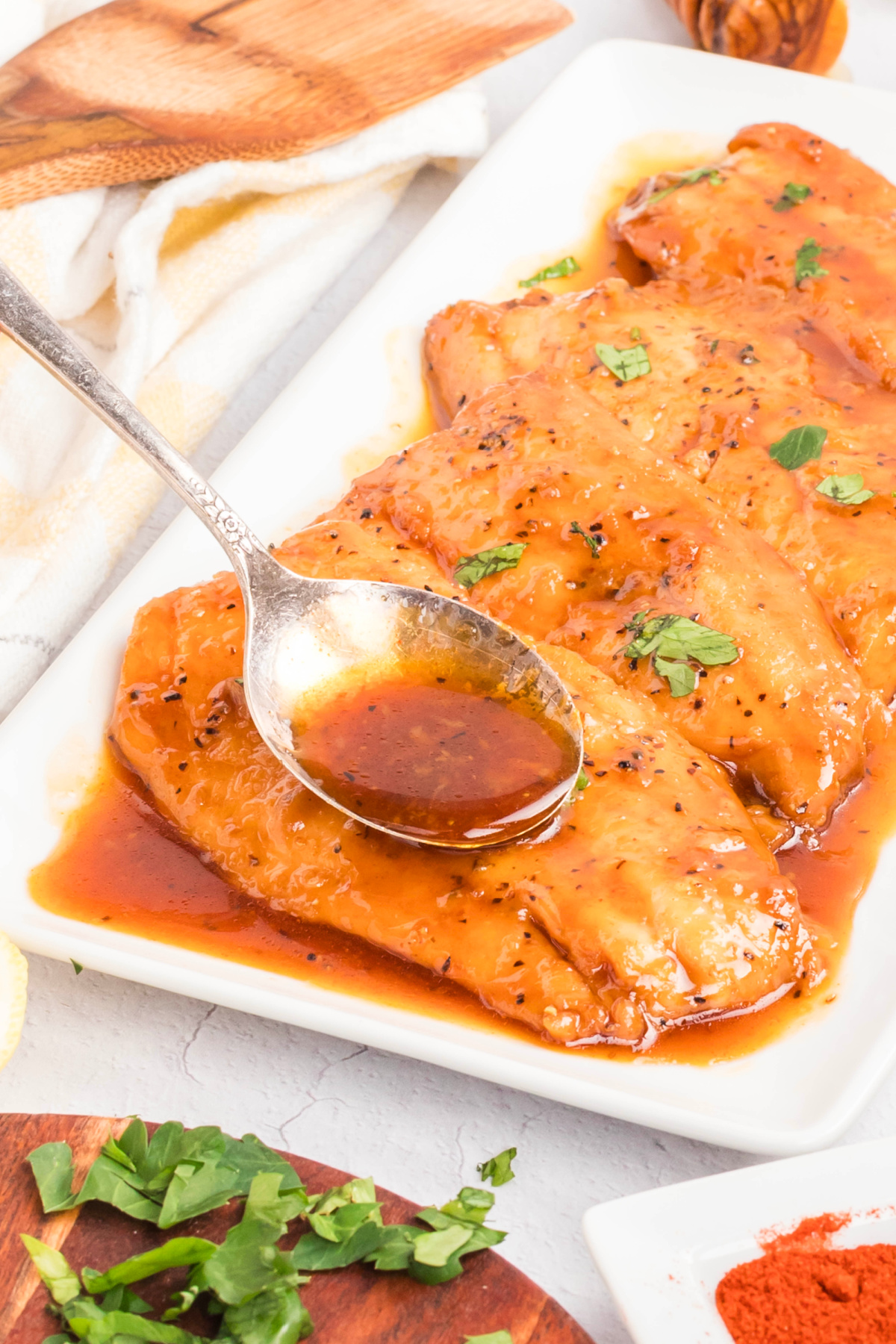 Glazed salmon fillets topped with lemon wedges and parsley, finished with a smooth honey soy glaze on a white platter.
