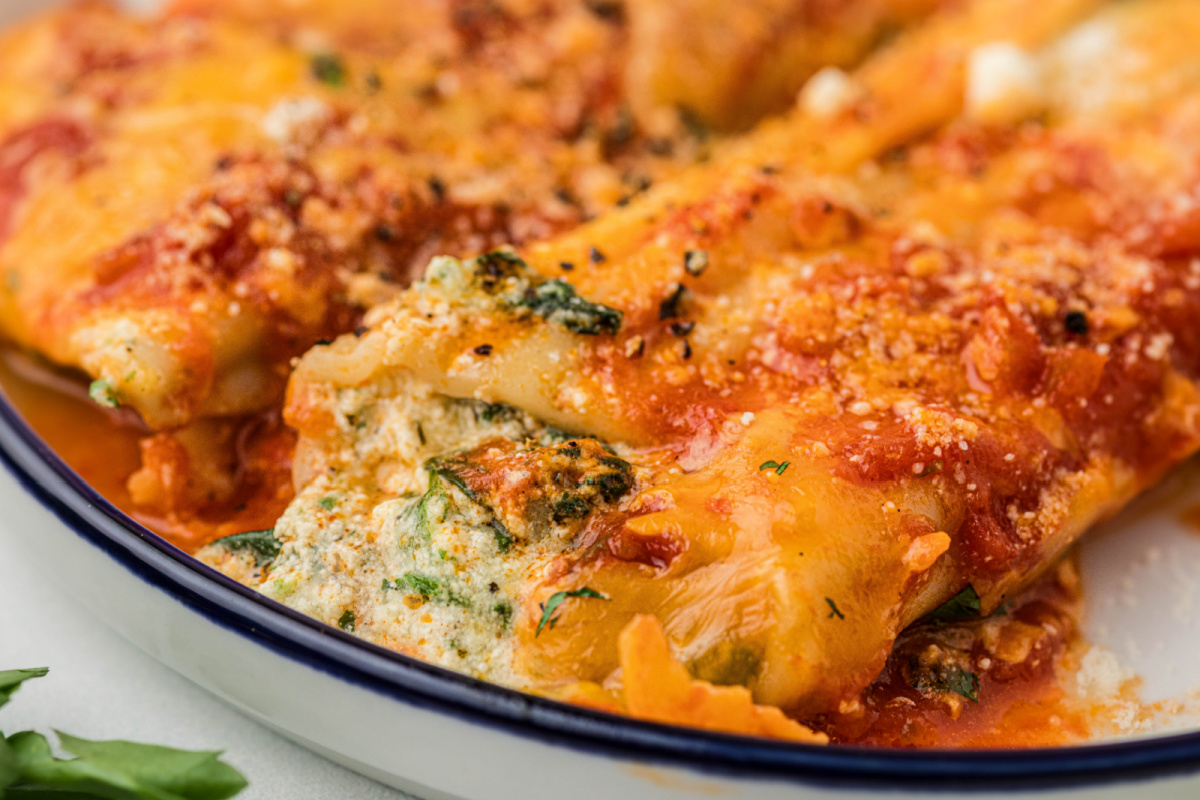 Close-up of baked manicotti with ricotta and spinach filling, marinara sauce, and melted cheddar cheese