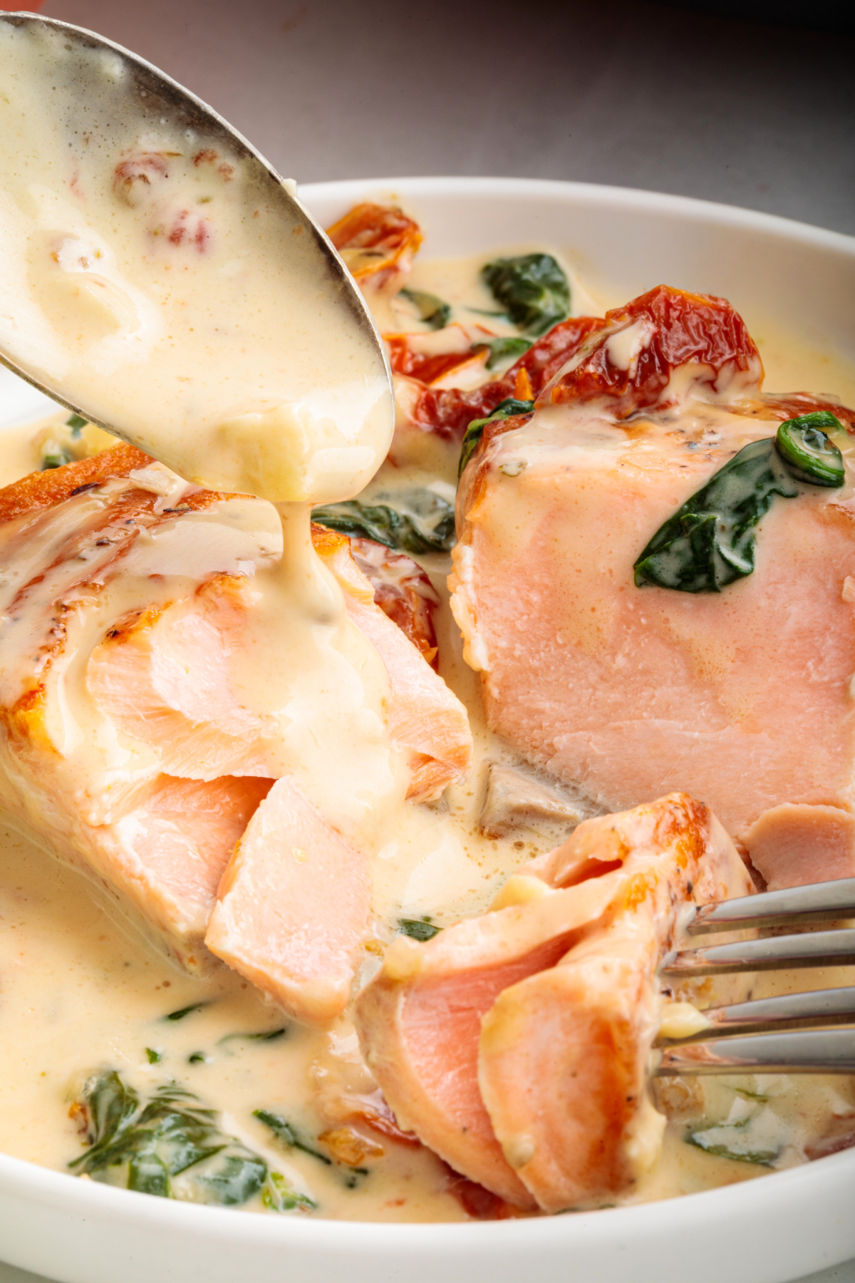 Marry Me Tuscan salmon flaking apart in a creamy garlic sauce with sun-dried tomatoes and spinach.