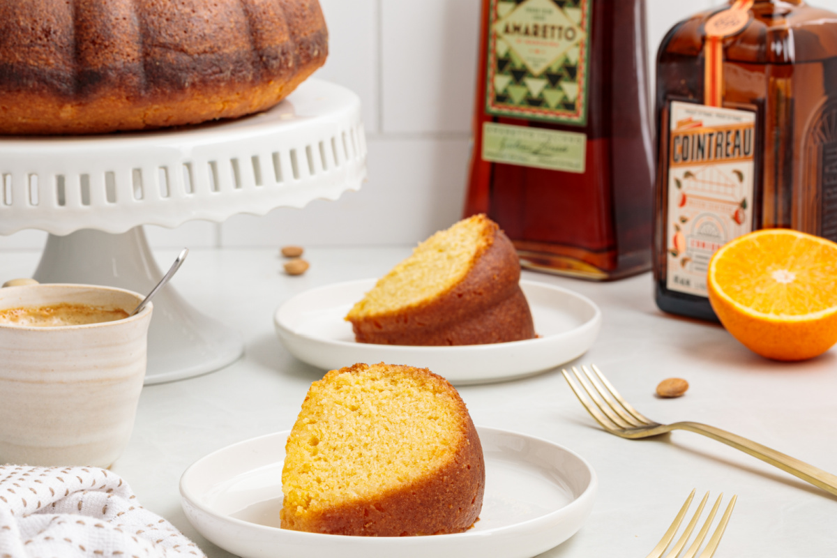 Slice of almond citrus olive oil cake served with espresso and liqueur bottles.