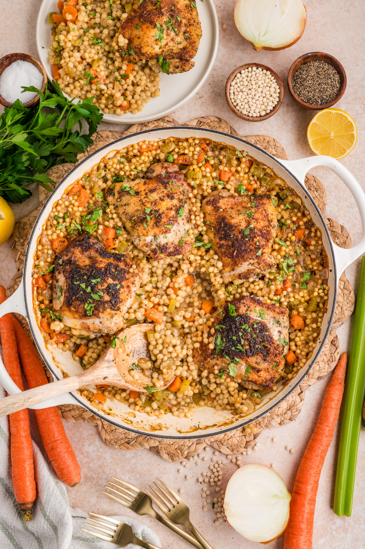 Crispy chicken thighs over pearl couscous baked in a braiser with carrots, celery, lemon, and herbs.