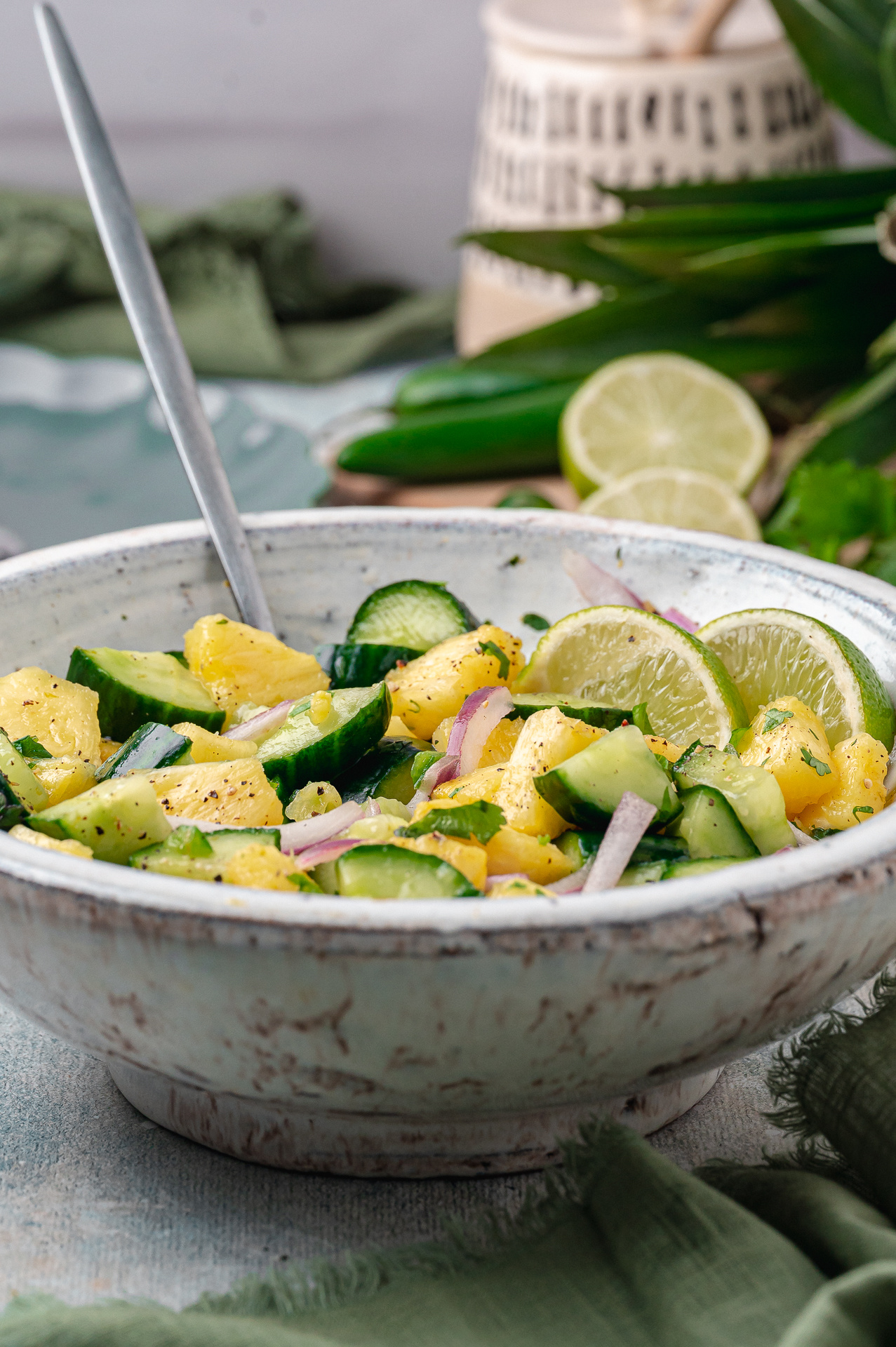 Forkful of chilled pineapple cucumber salad with pineapple, cucumber, red onion, and cracked black pepper.