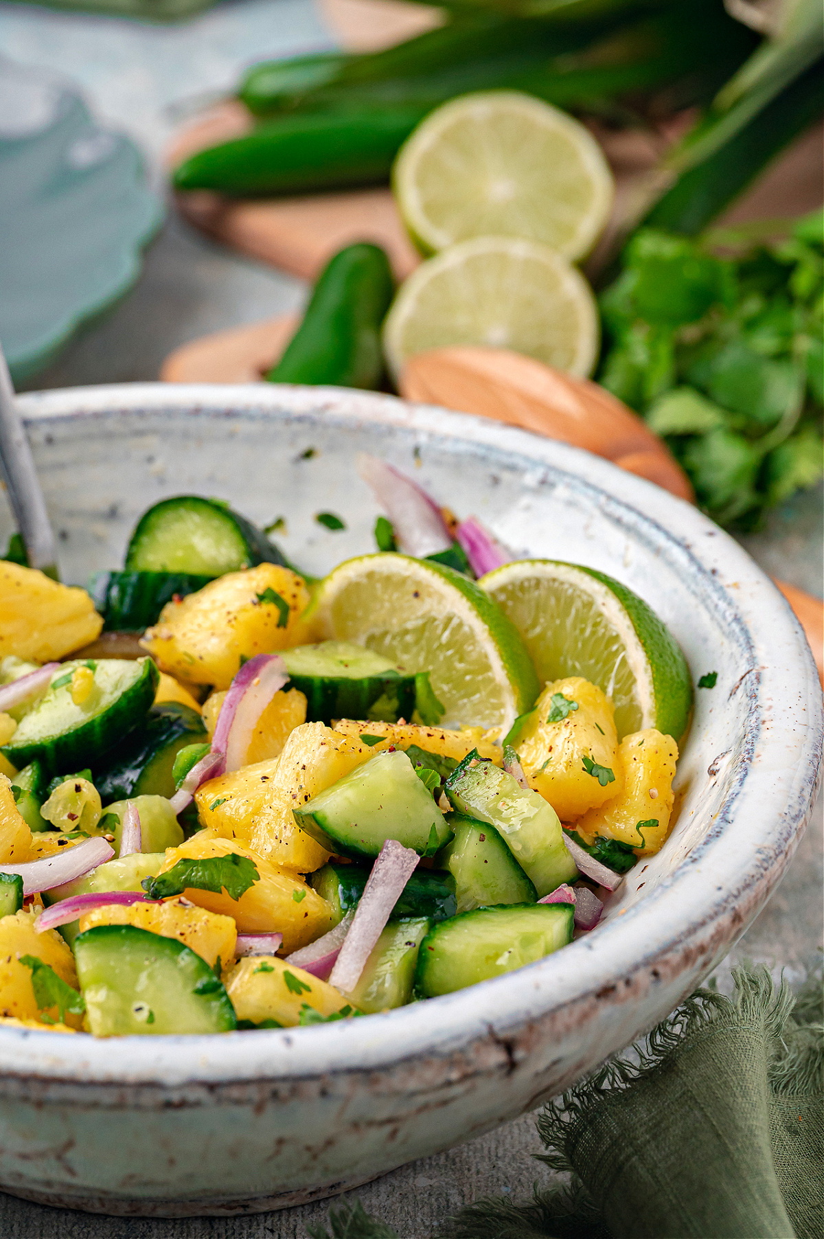 Chilled pineapple cucumber salad with fresh pineapple chunks, sliced cucumber, red onion, cilantro, and lime slices in a ceramic bowl.