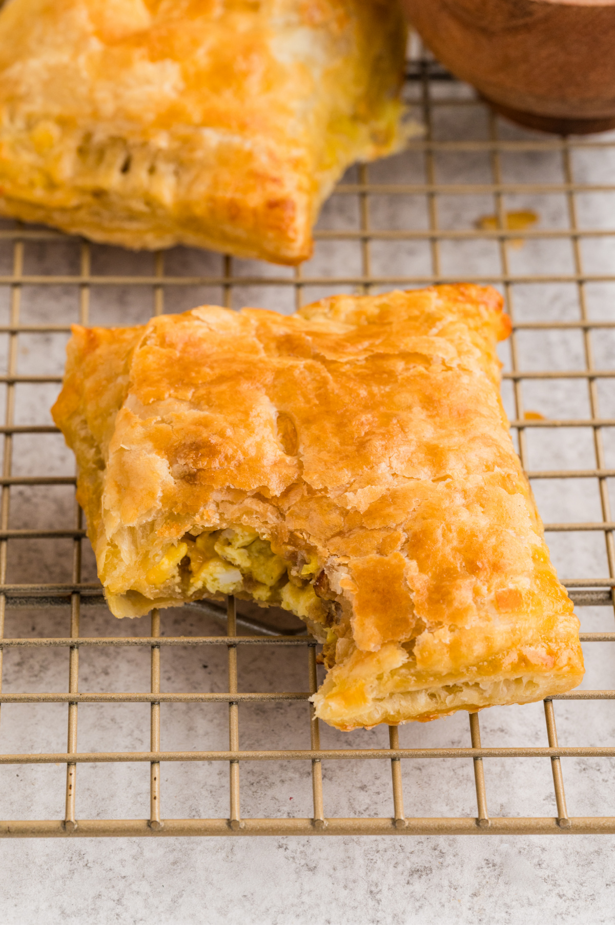 a bite taken out of the breakfast pastry with sausage and eggs