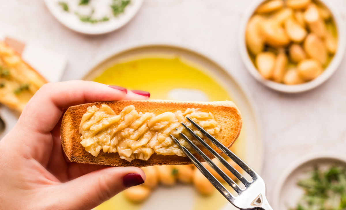 Garlic confit cloves served on toasted bread, shown close up and ready to eat.