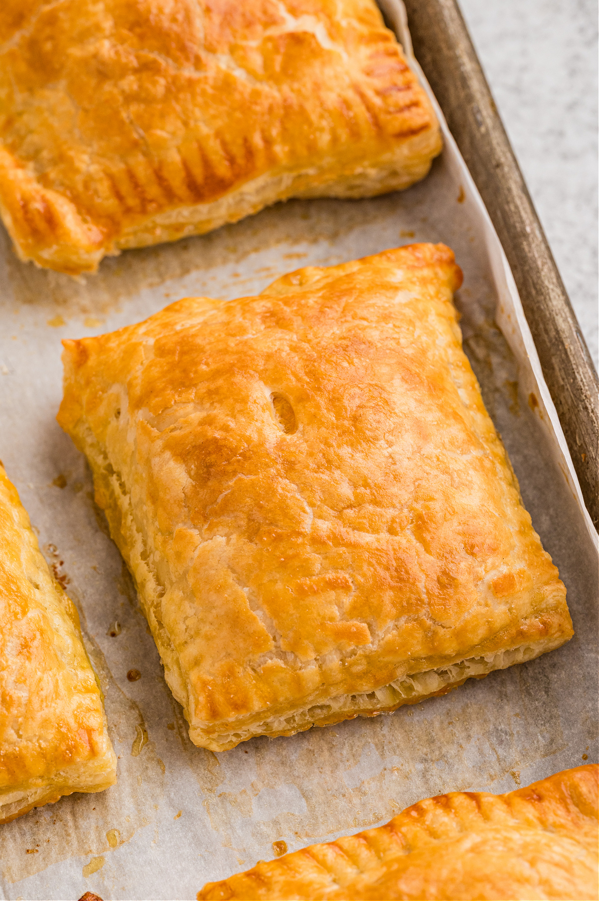Flaky sausage, egg, and cheese breakfast pastries baked until golden on a parchment-lined baking sheet.