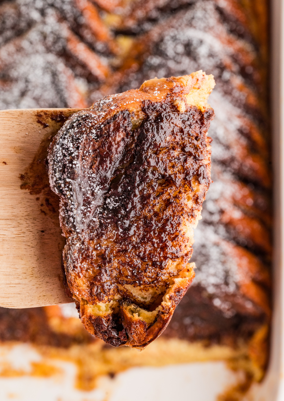 Slice of Nutella French Toast Bake lifted from the pan showing melted chocolate hazelnut layers and custard-soaked brioche