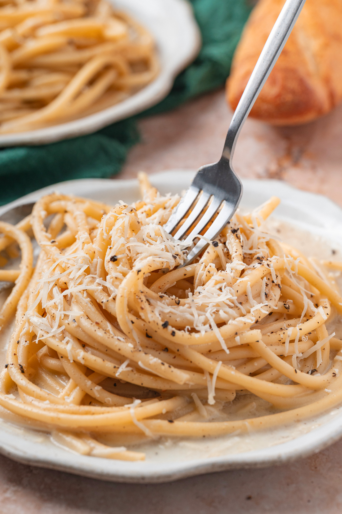 Cacio e Pepe with fork lifting strand of buttered pasta