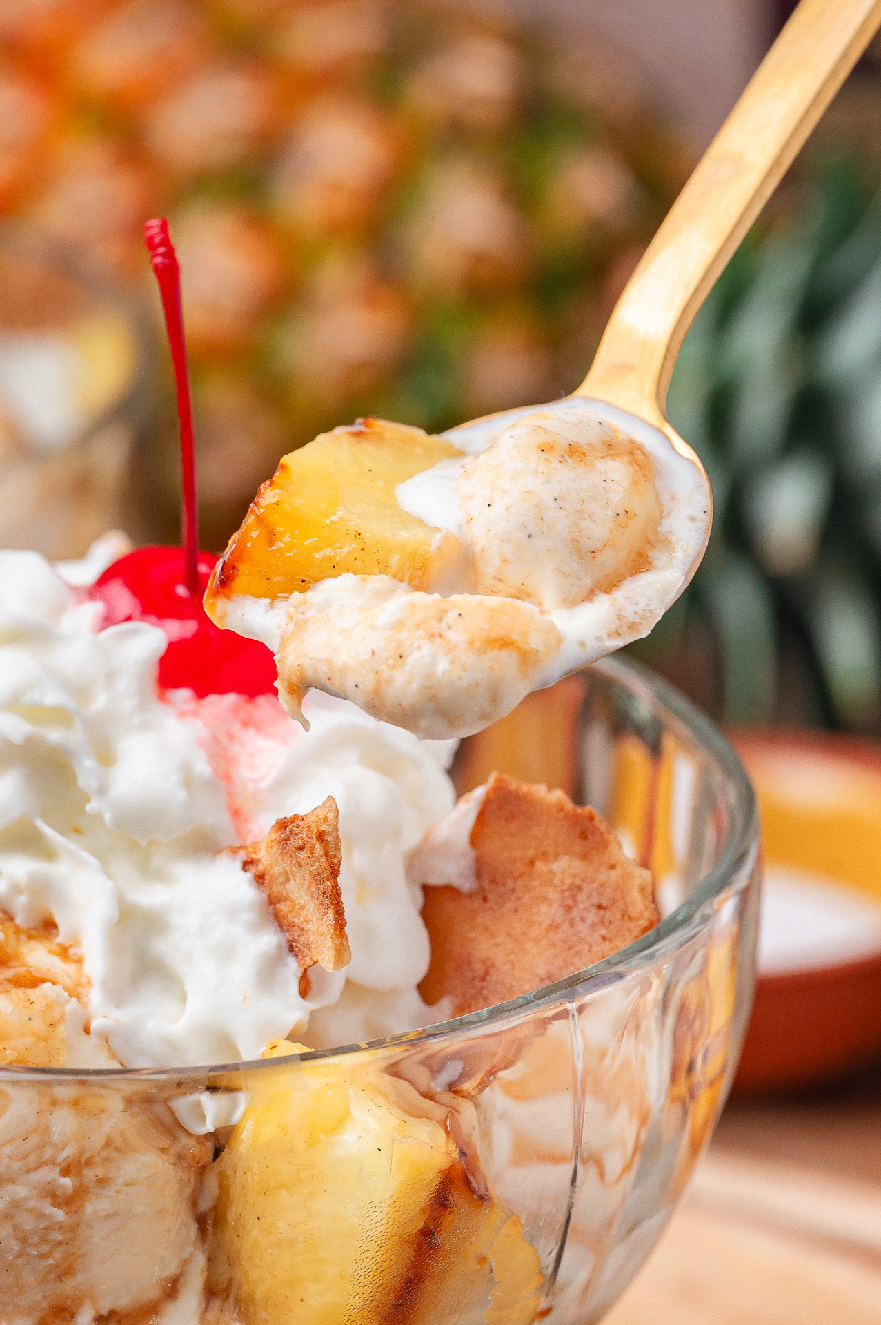Spoonful of grilled pineapple sundae with hot buttered rum sauce and melting vanilla ice cream