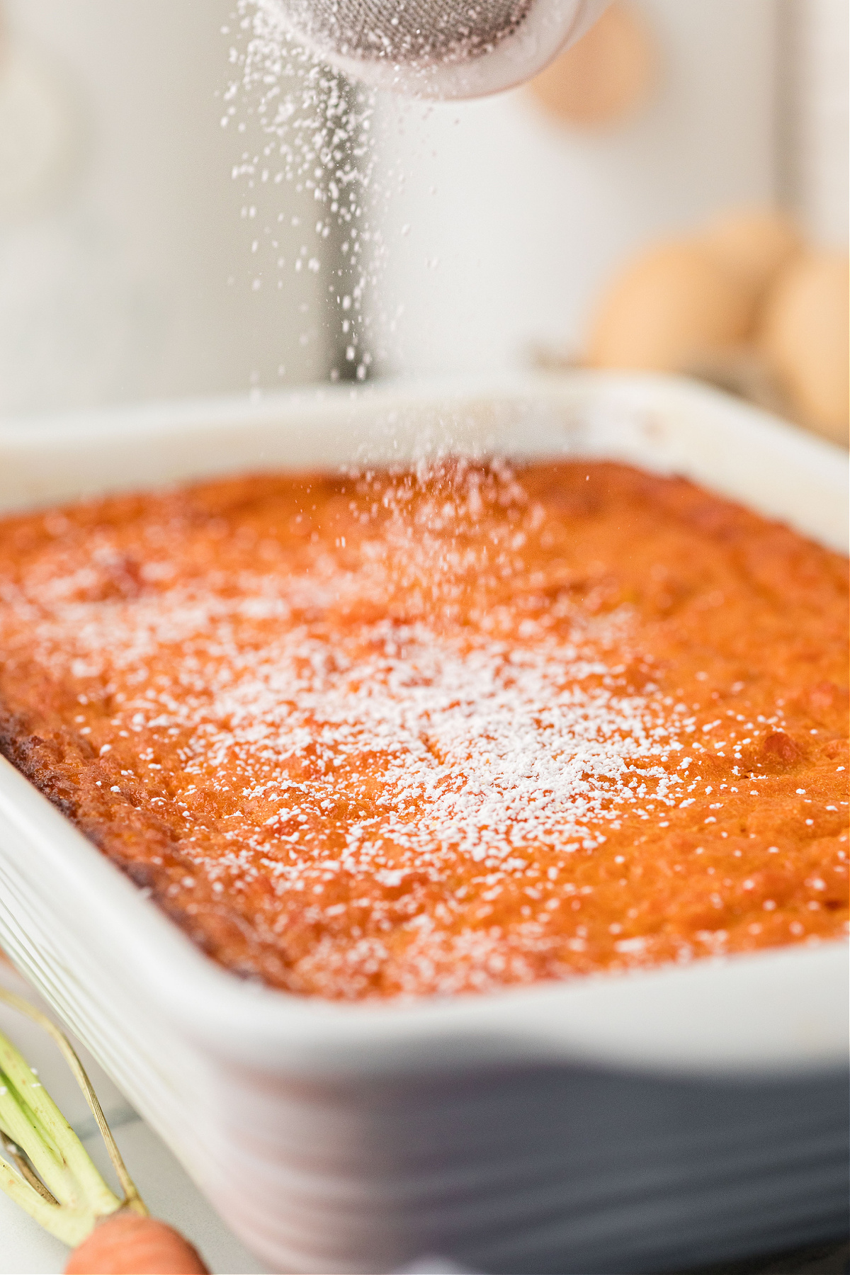 Baked carrot casserole with powdered sugar in white 11x7 baking dish