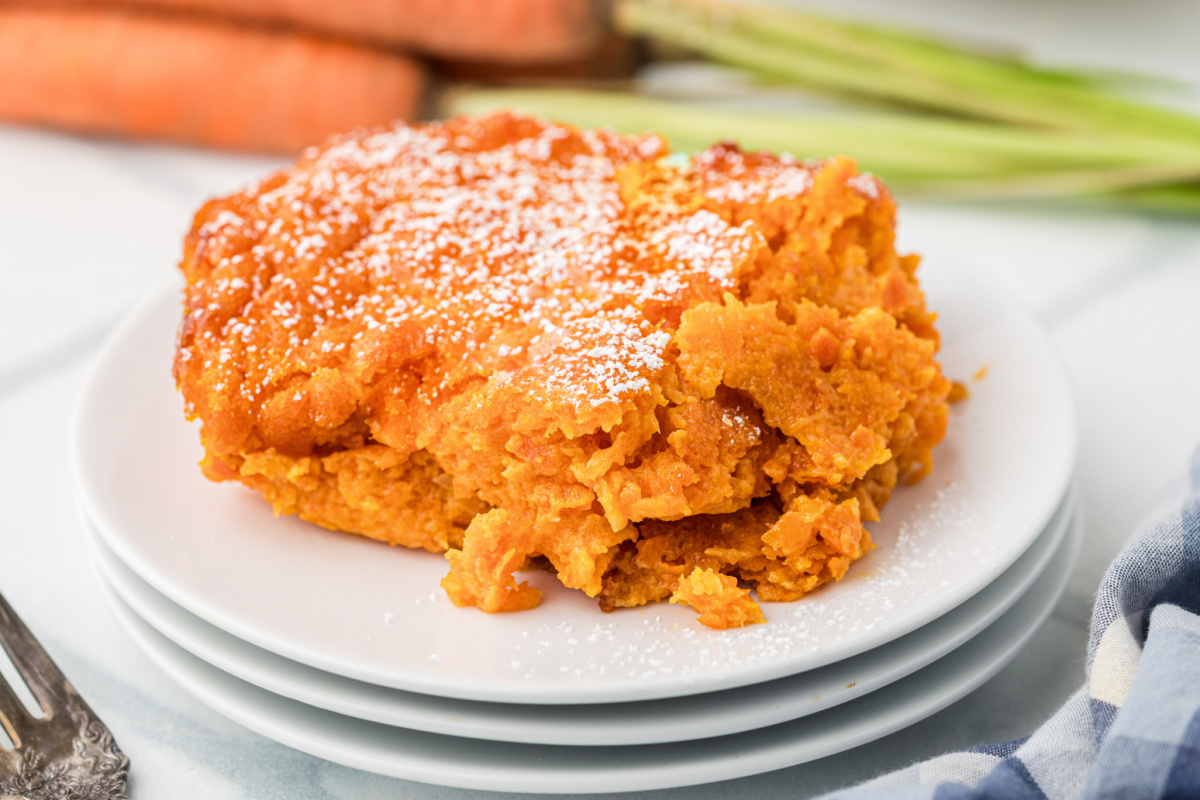 Slice of Carrot Souffle dusted with powdered sugar served on a white plate