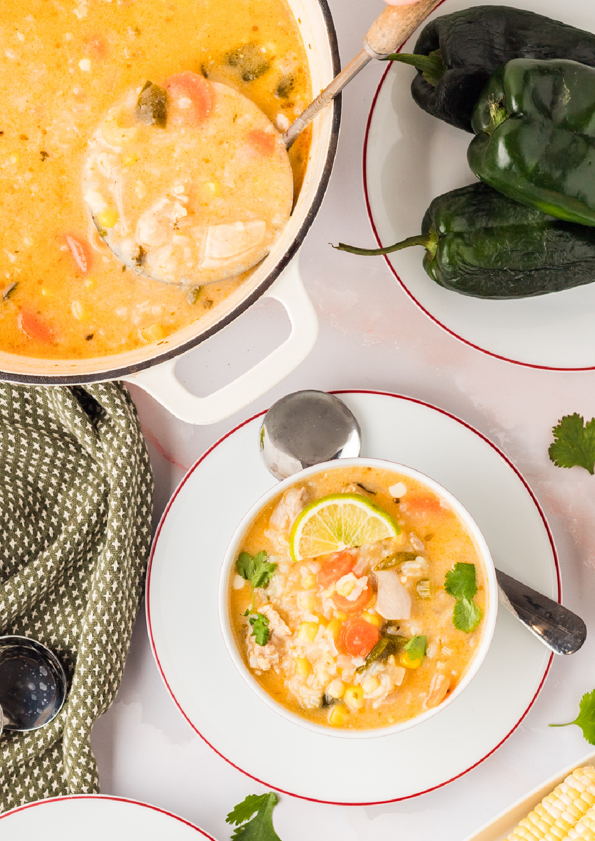 Overhead view of creamy chicken and rice soup with charred poblano, corn, and lime garnish