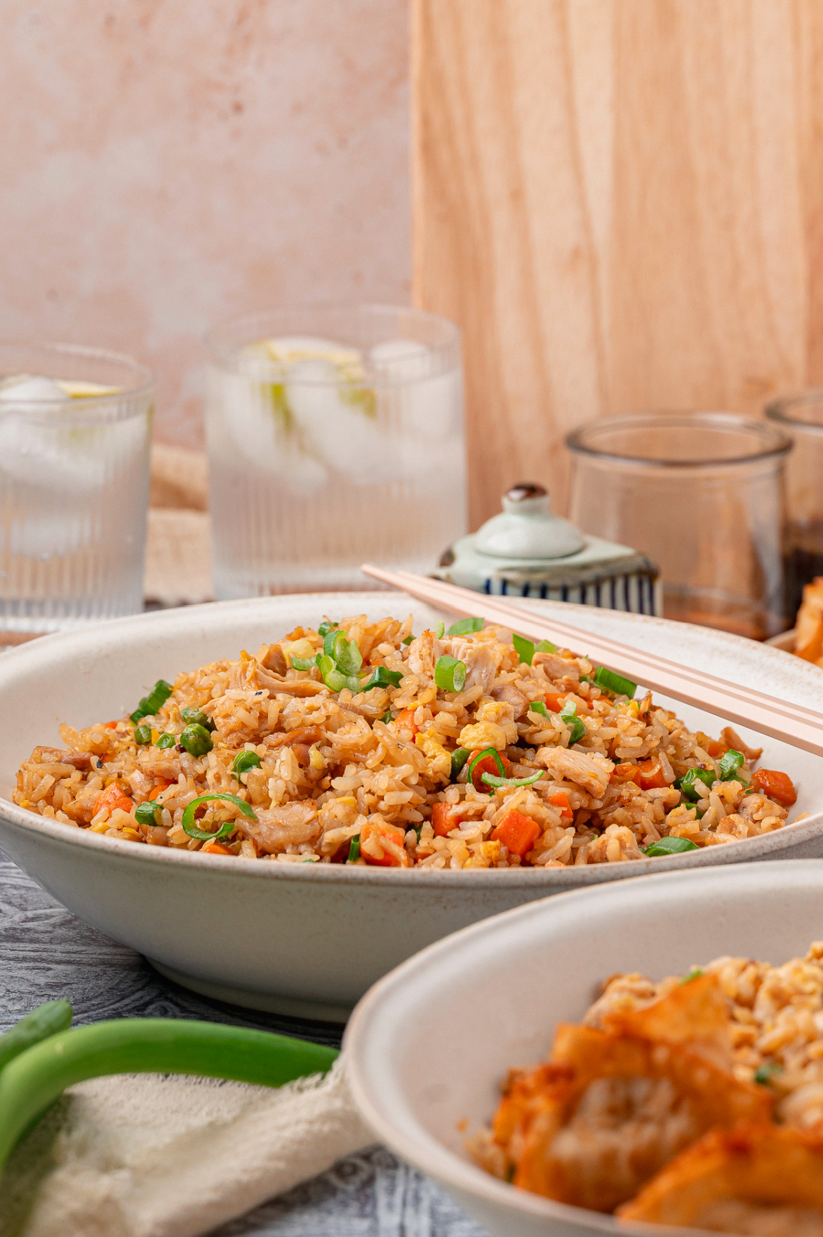 Homemade fried rice with chicken, eggs, peas, carrots, and green onions served in a wide bowl