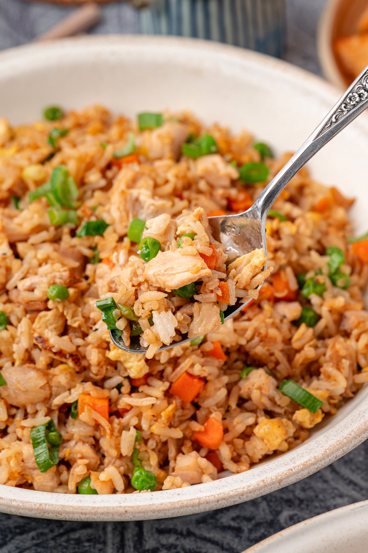 Fried rice with chicken, eggs, peas, carrots, and green onions served in a bowl