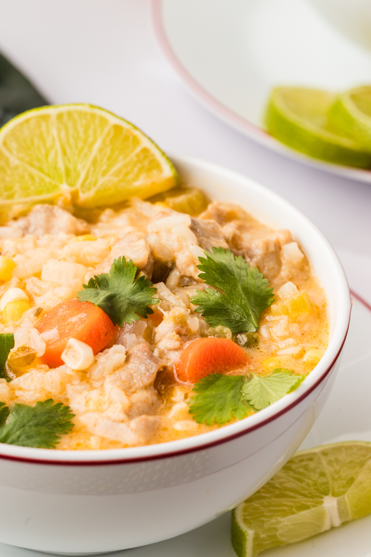 Creamy Chicken and Rice Poblano Soup with corn, carrots, cilantro, and fresh lime wedges