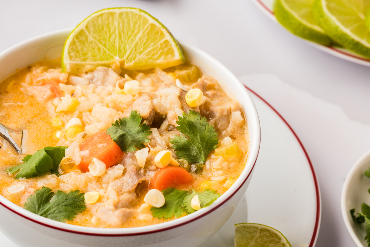 Creamy Chicken and Rice Poblano Soup topped with corn, cilantro, and fresh lime