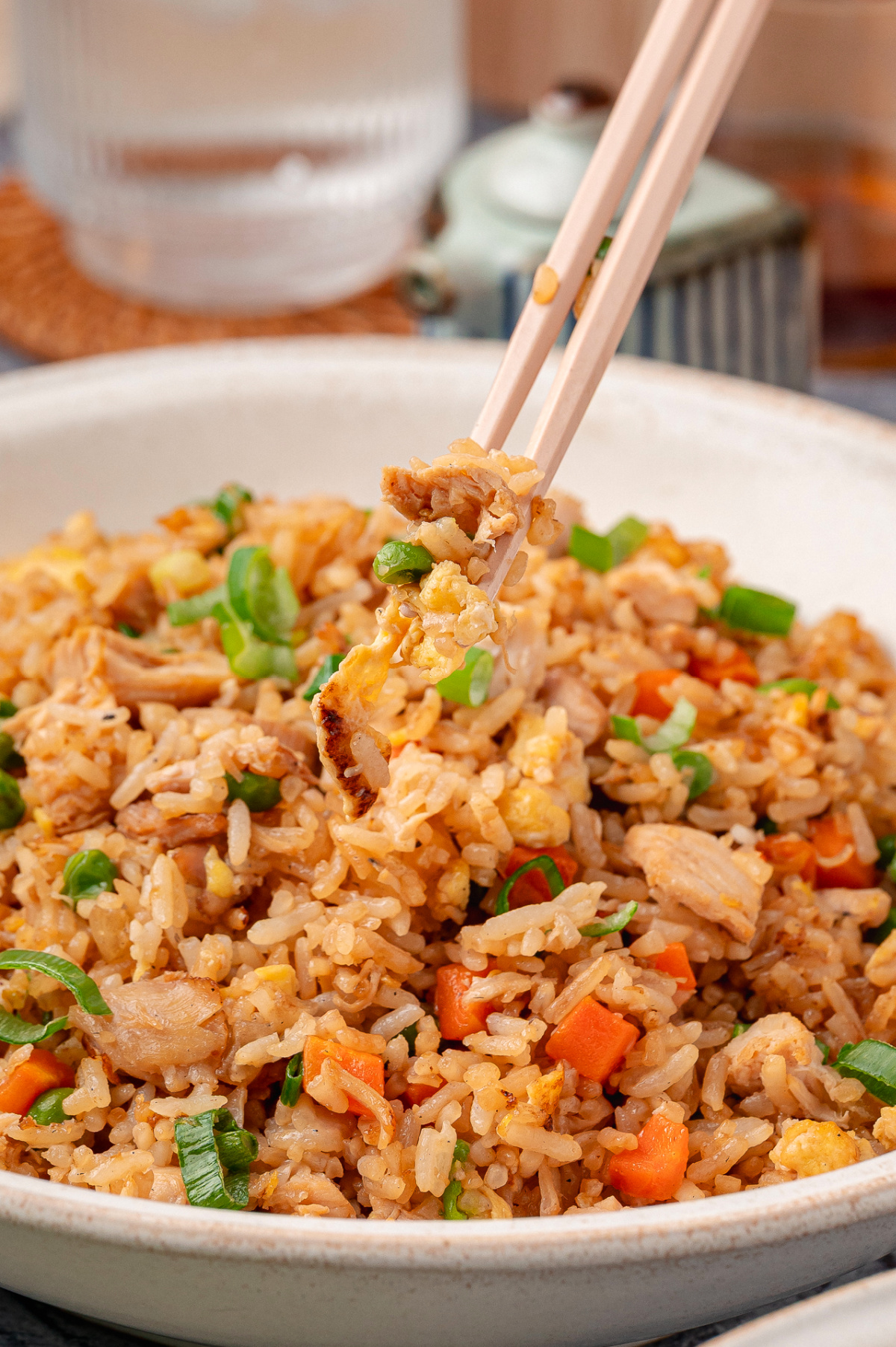 Chicken fried rice with rotisserie chicken, eggs, vegetables, and green onions in a bowl