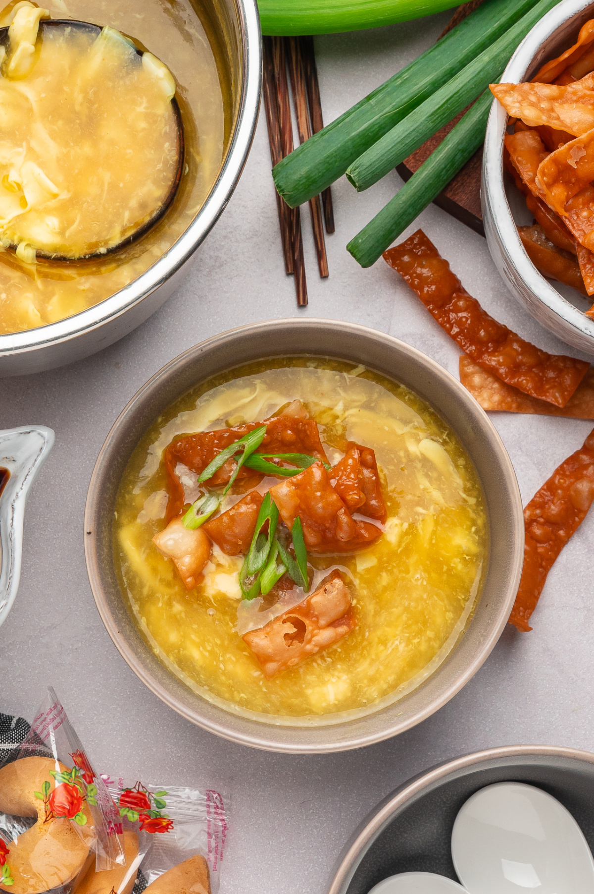 Egg drop soup with fried wonton strips served with soft egg ribbons and green onions
