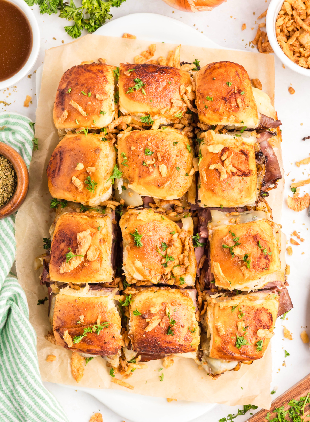 French dip sliders baked on sweet rolls with roast beef, provolone cheese, and French-fried onions